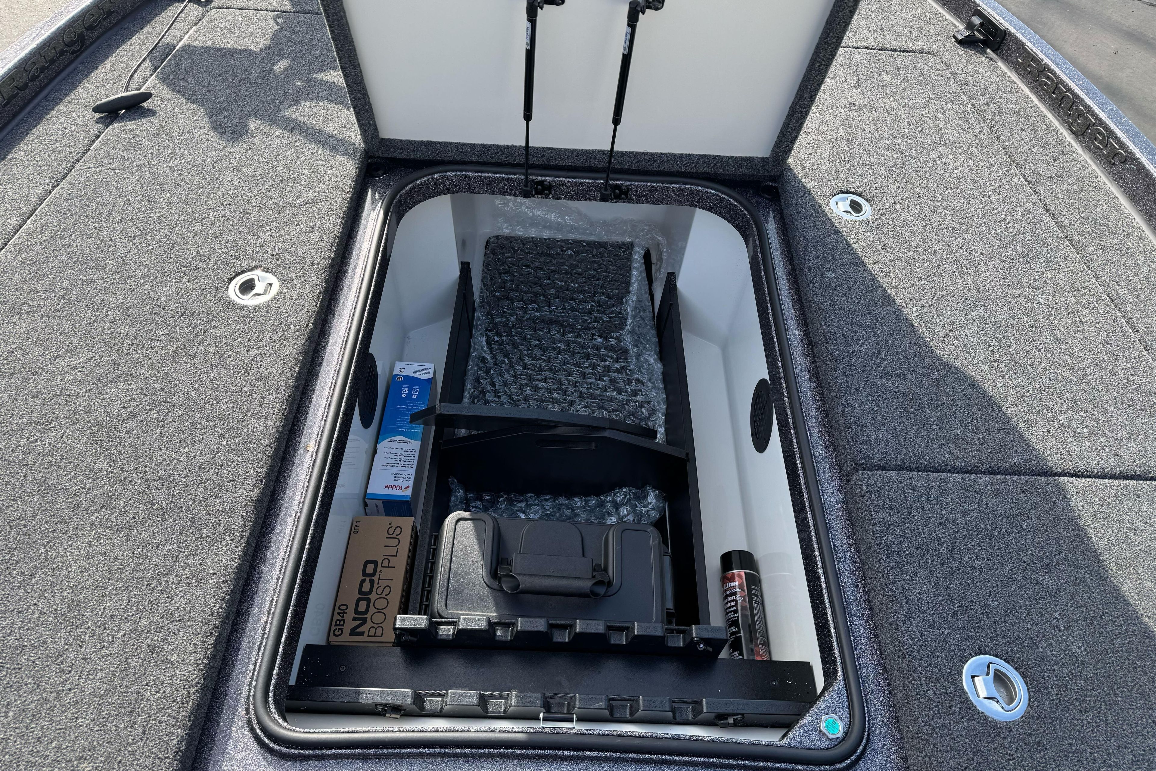 2025 Ranger Z521 boat storage compartment with various items, including a Noco Boost Plus.