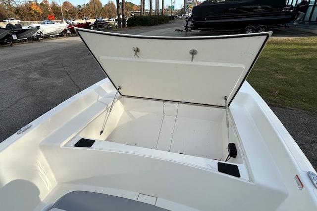 2025 Mako Pro Skiff 17 CC boat with open storage compartment, parked outdoors.