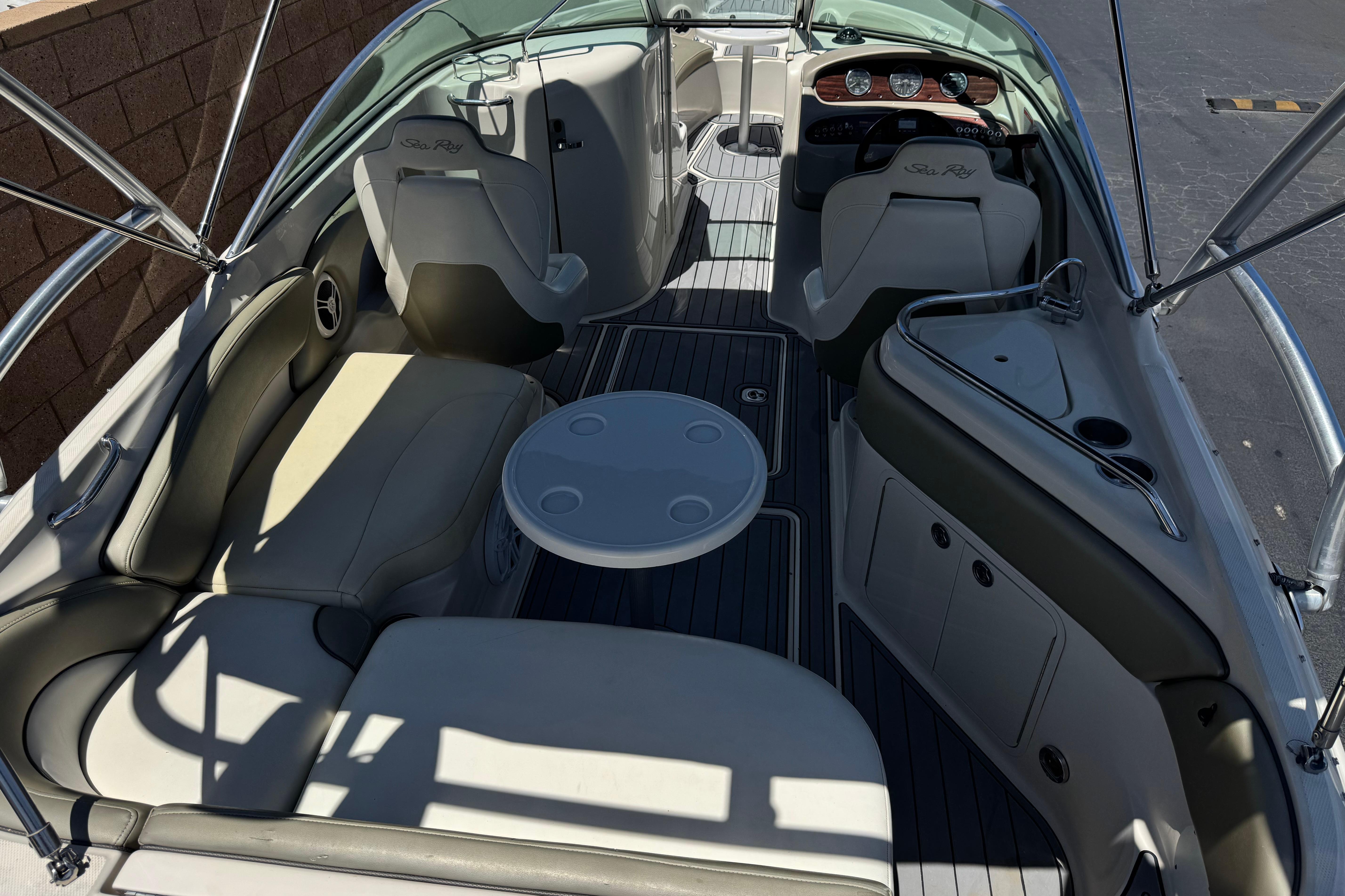 2007 Sea Ray 240 Sundeck interior with seating, table, and helm, showcasing luxury boat design.