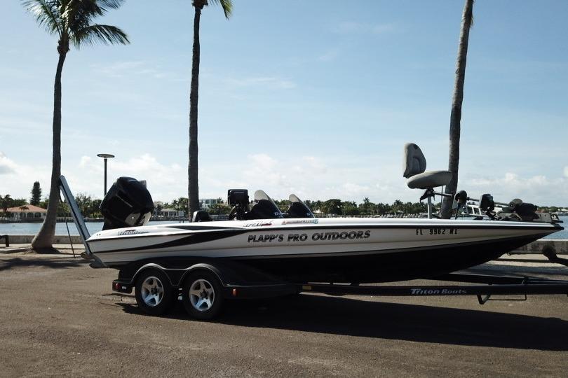 2005 Triton Tr-21X PD boat on trailer by waterfront, palm trees in background.