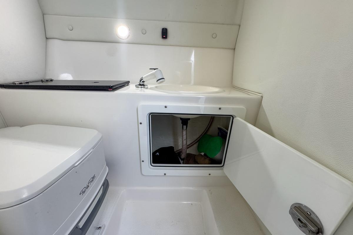 2022 Velocity 290sc boat interior with compact bathroom and storage compartment.