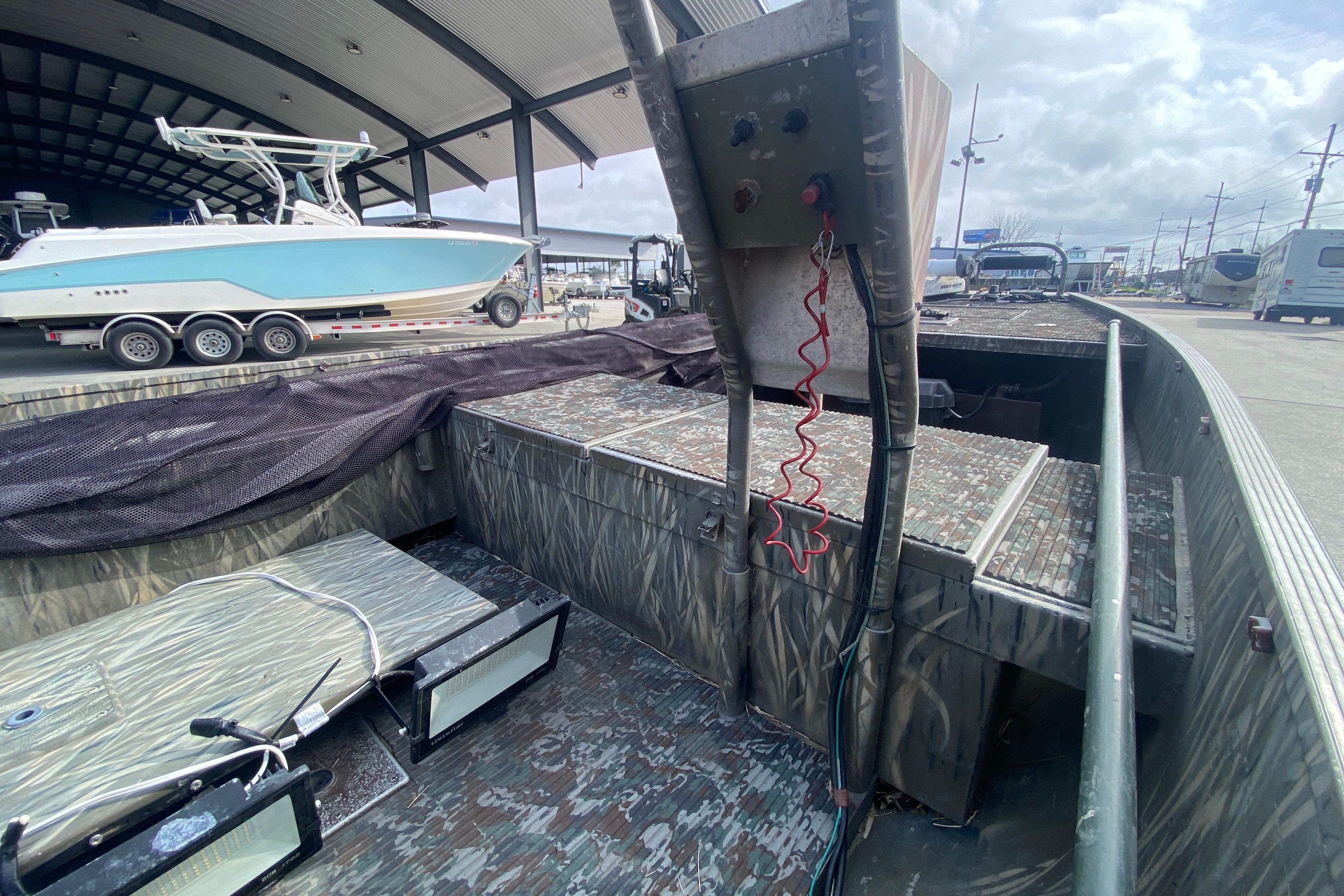 2009 Gator Trax MUD BUDDY 17 X 50 boat with camo interior, parked under shelter.