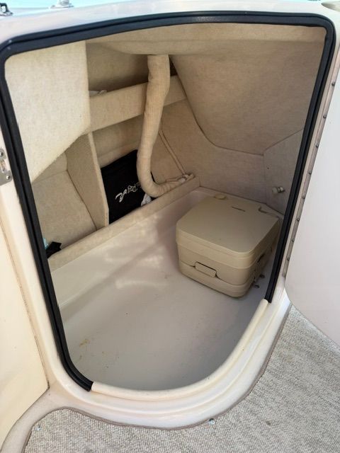 Interior of a Sea Ray 210 Sundeck with storage space and a portable toilet.