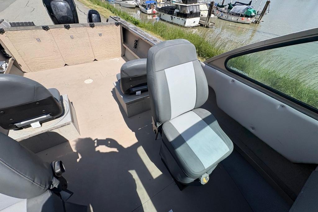 2009 Alumaweld Intruder Outboard 22 interior with gray seating, docked near boats.