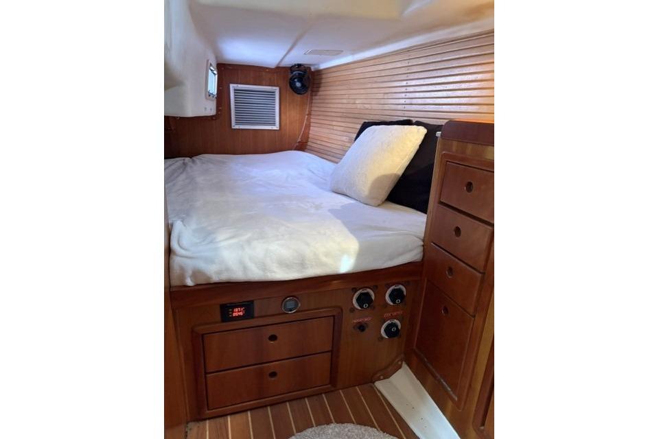 Cozy cabin interior of 2002 Saga 43 yacht with wooden finish and comfortable bedding.