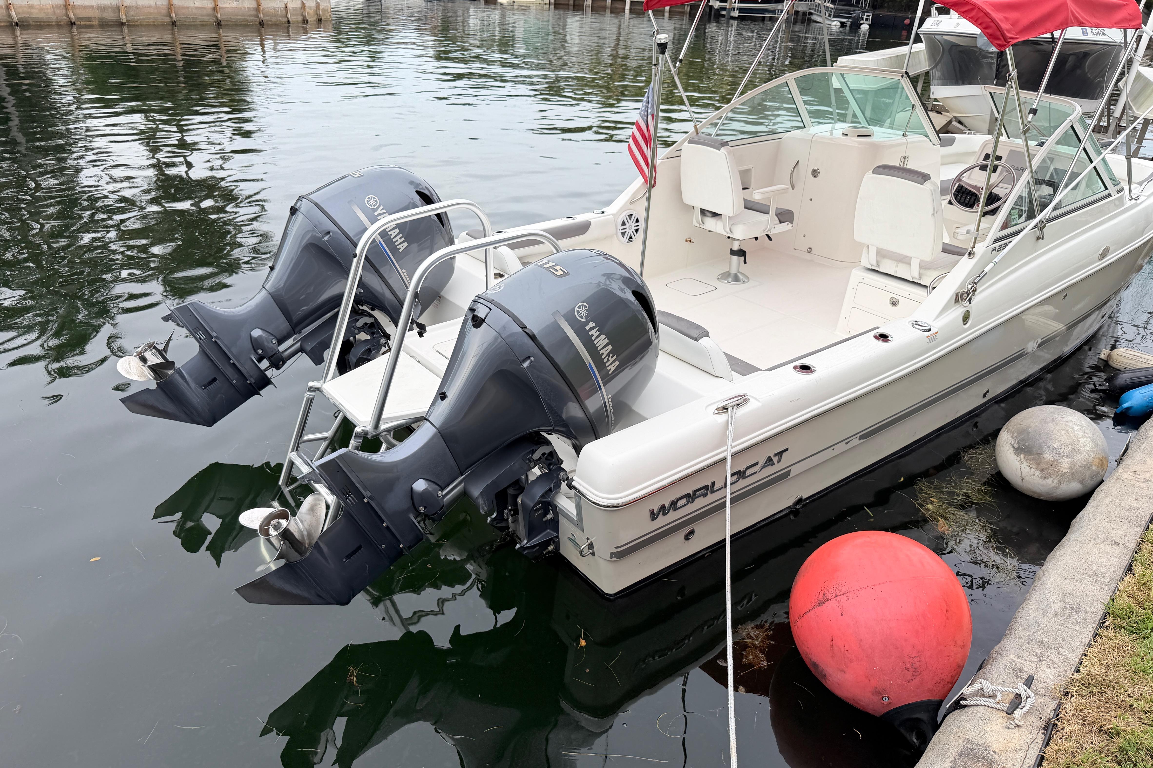 2019 World Cat 230 DC boat with dual Yamaha engines docked by the water.