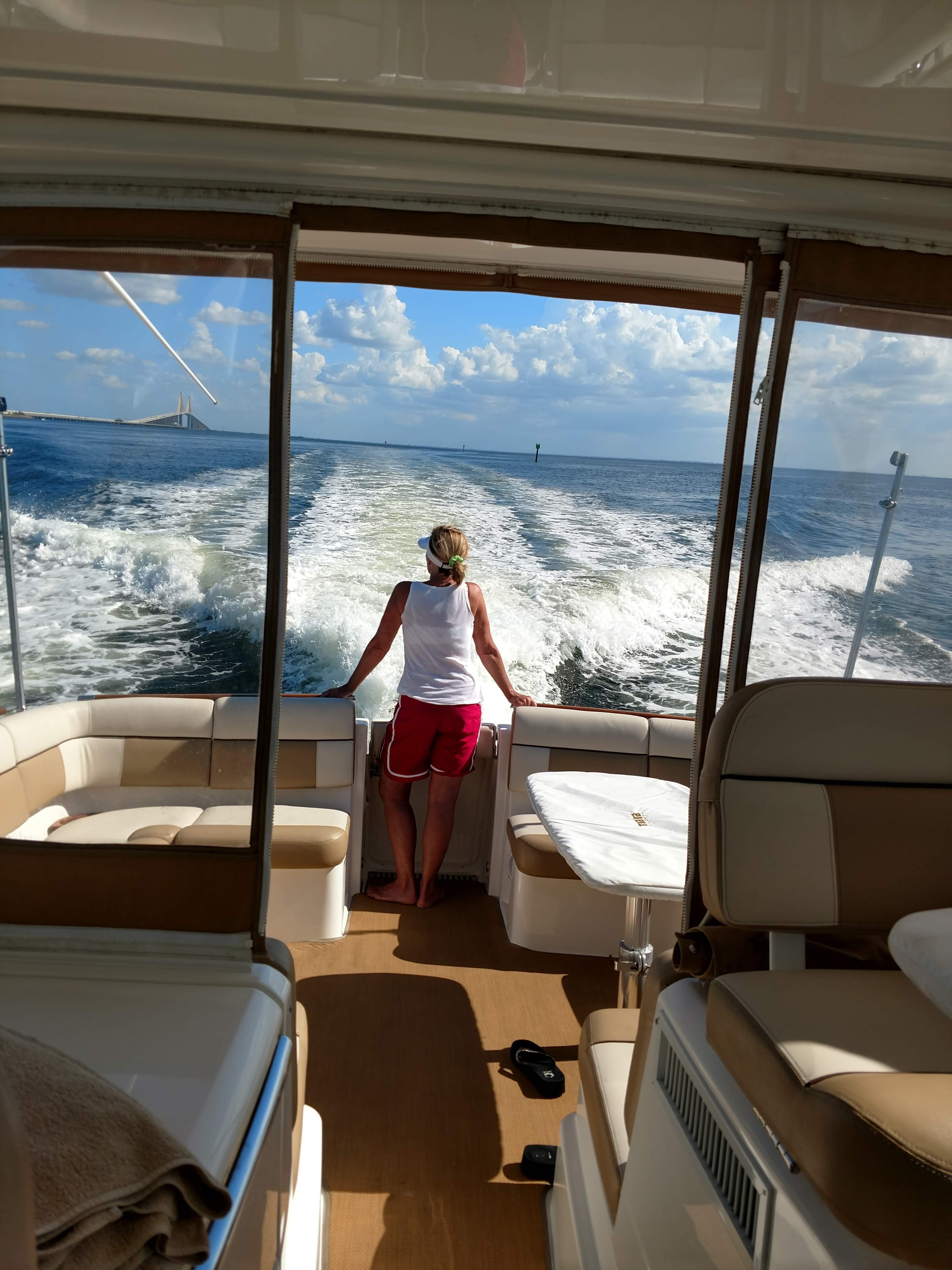 Woman stands on a boat, looking at the water as it moves.