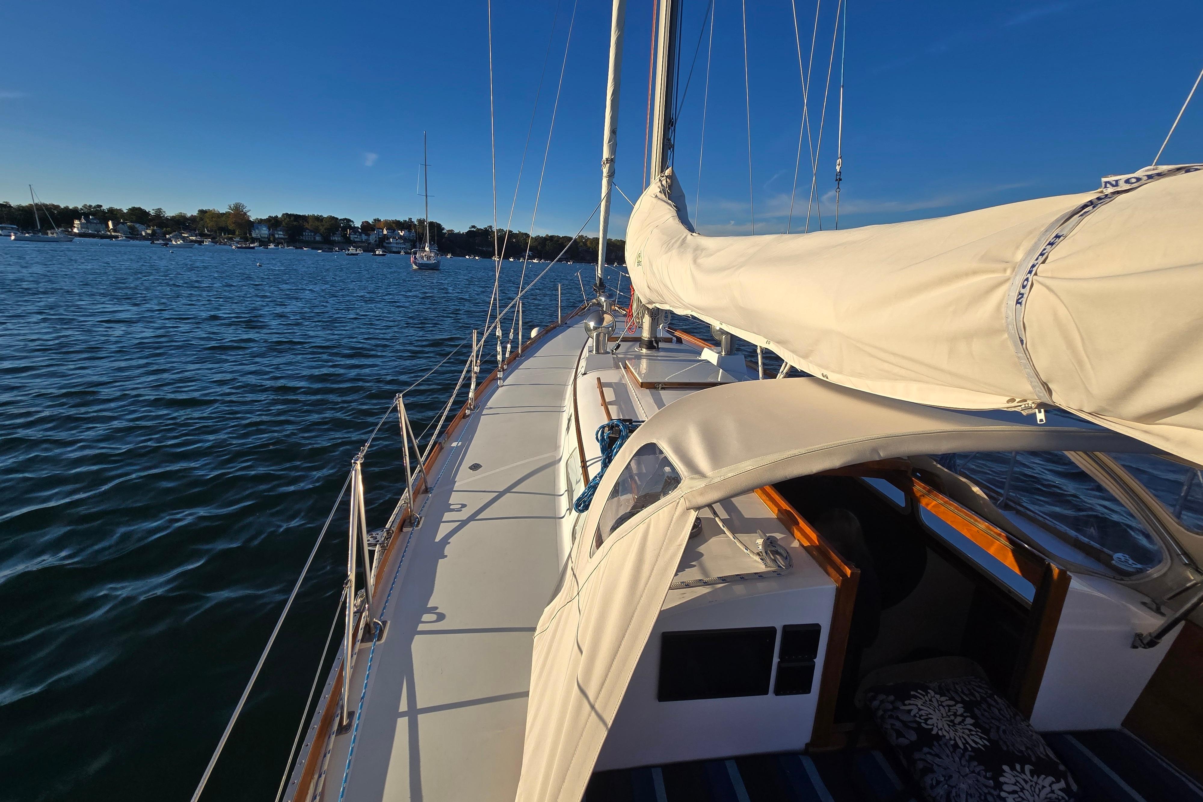 1970 Hinckley Bermuda 40 sailboat on calm waters under clear blue sky.