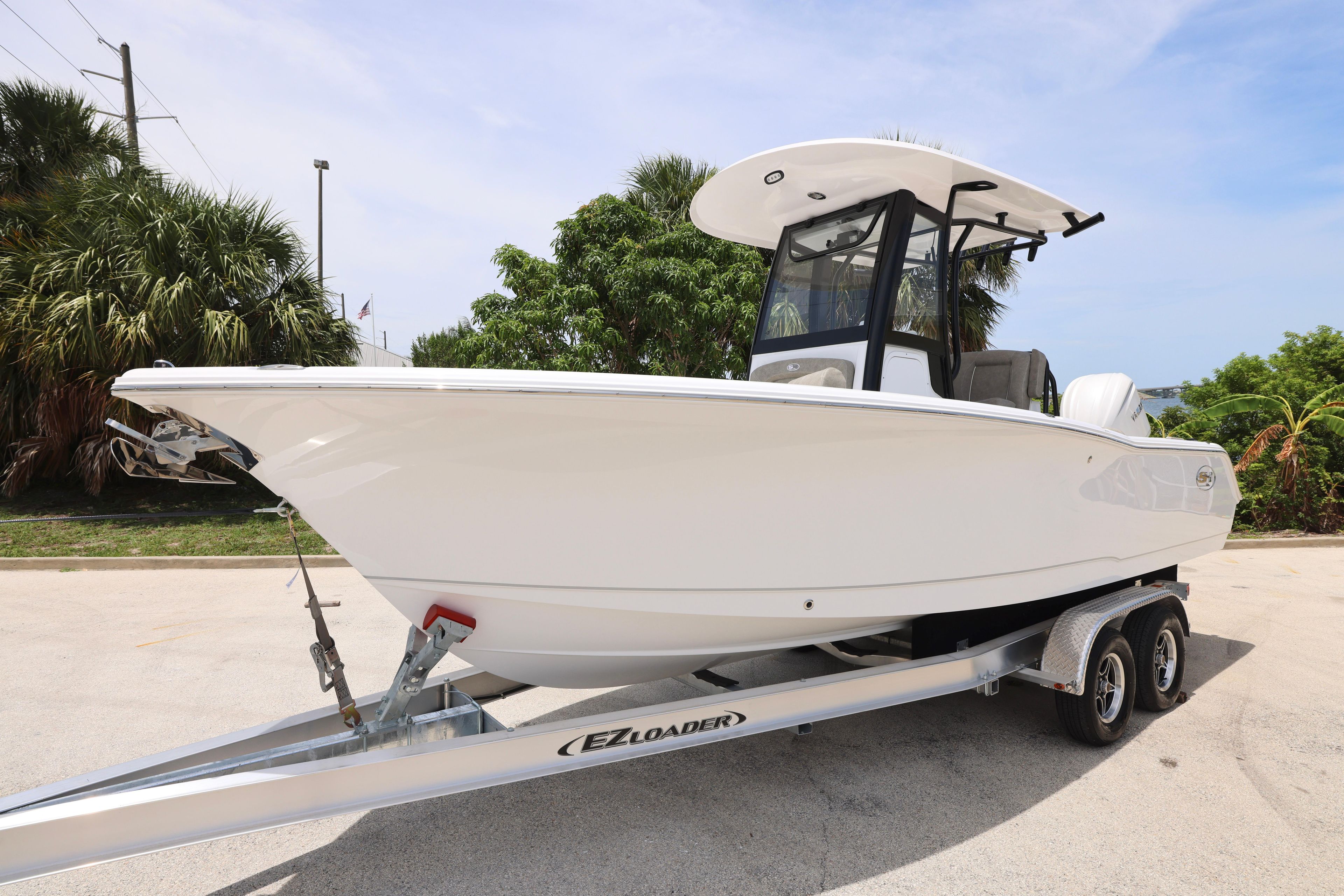 2026 Sea Hunt Ultra 245 SE boat on trailer, parked outdoors, surrounded by greenery.
