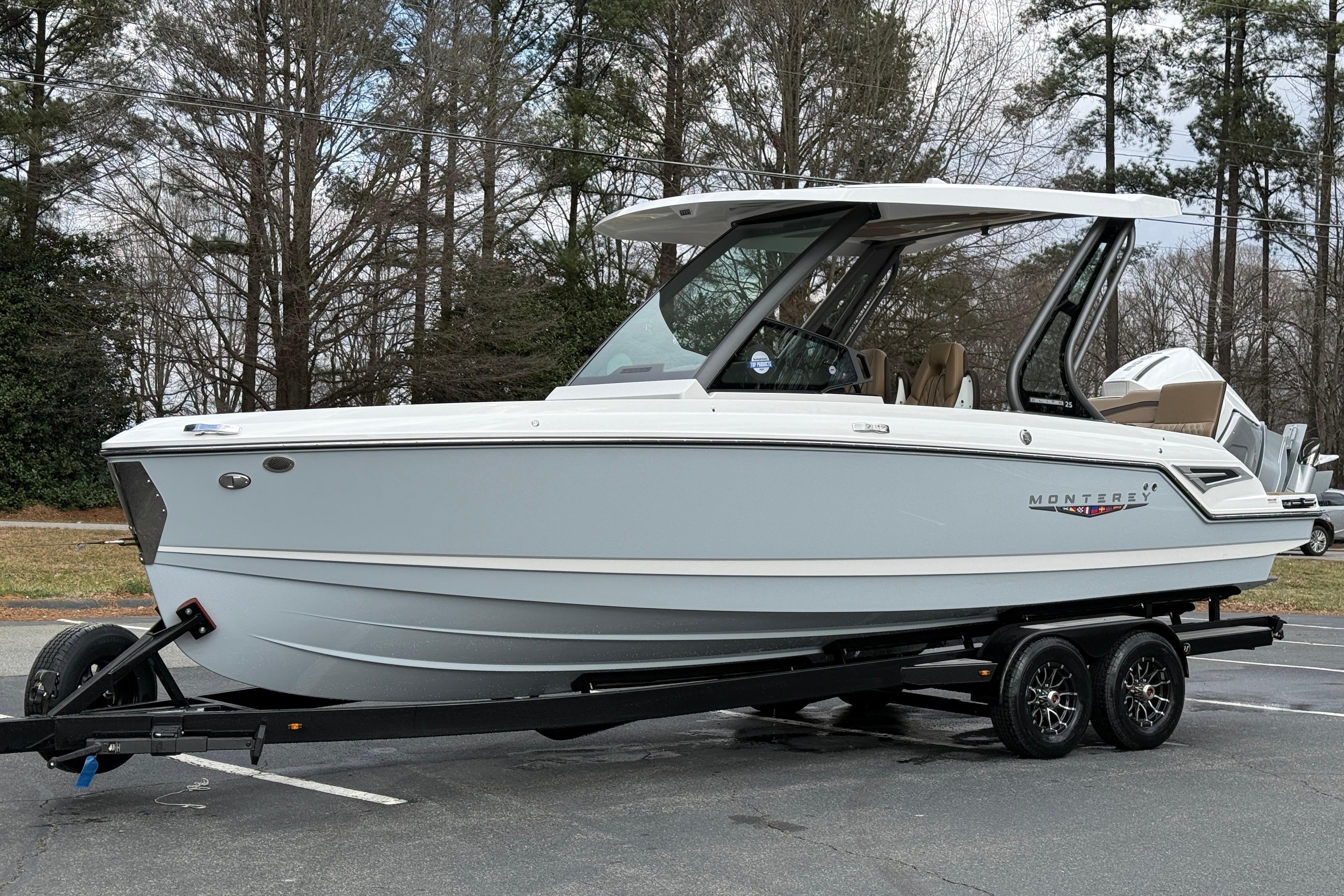 2026 Monterey Elite 25 OB boat on trailer, parked outdoors.