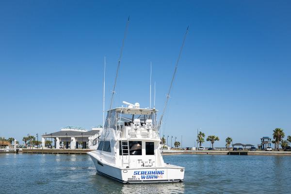 1999 Viking 47 Convertible yacht on calm water under clear blue sky.