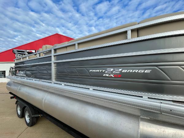 2024 Sun Tracker Party Barge 22 XP3 pontoon boat with trailer, docked outdoors.