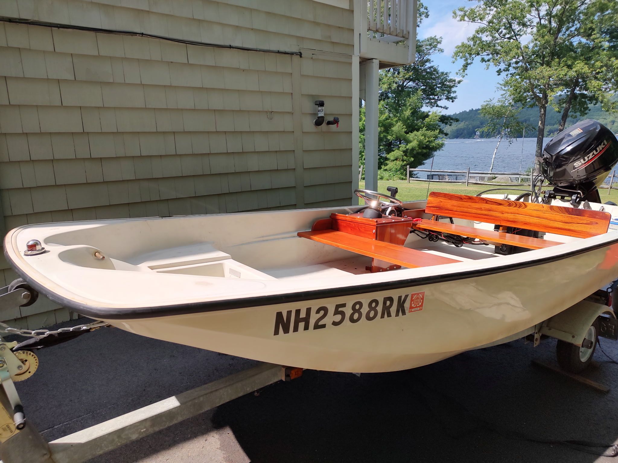 A 1987 Boston Whaler Sport 13 on a trailer. It features wooden benches and an outboard motor.
