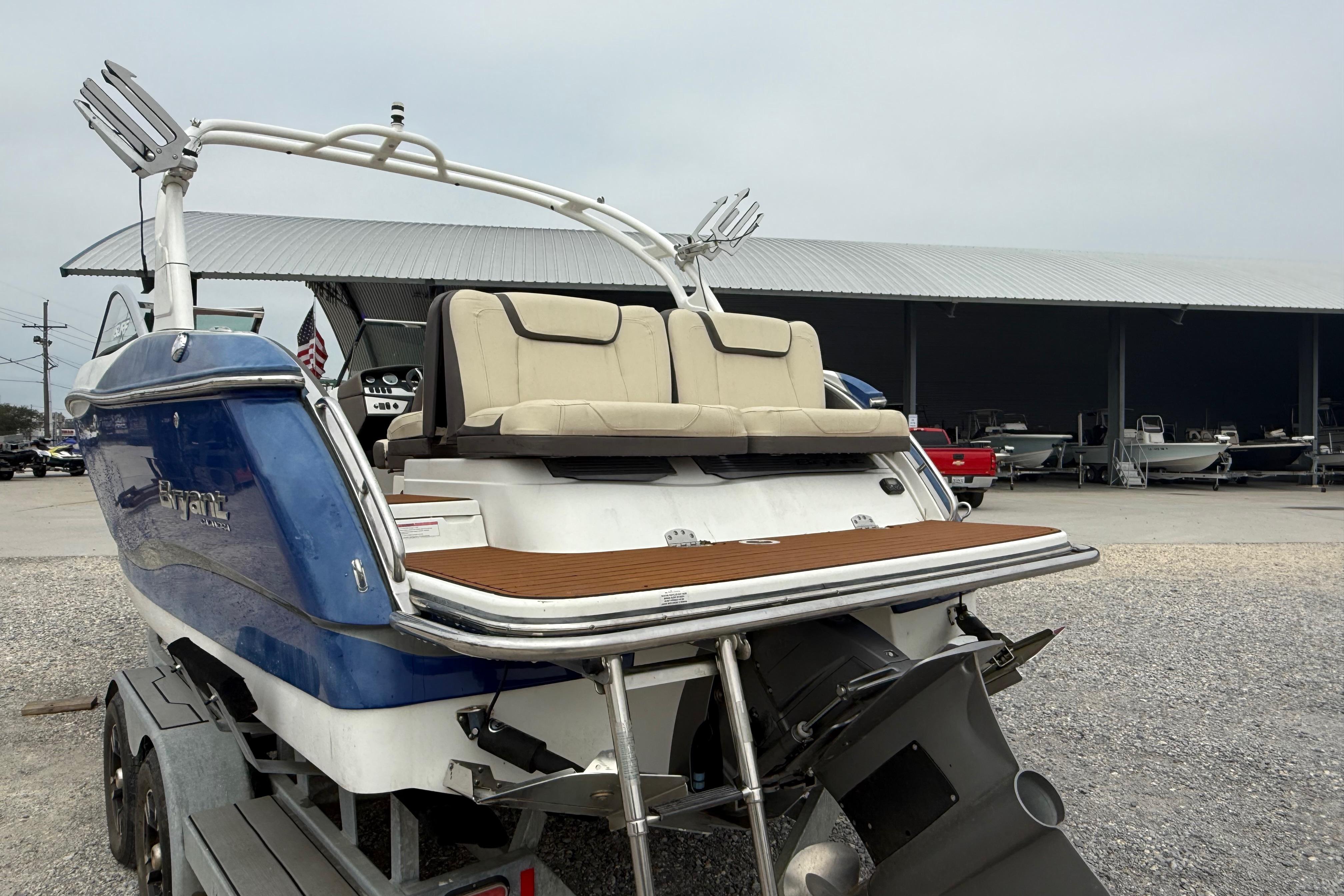 2018 Bryant Calandra boat with blue hull on trailer, featuring rear seating and swim platform.