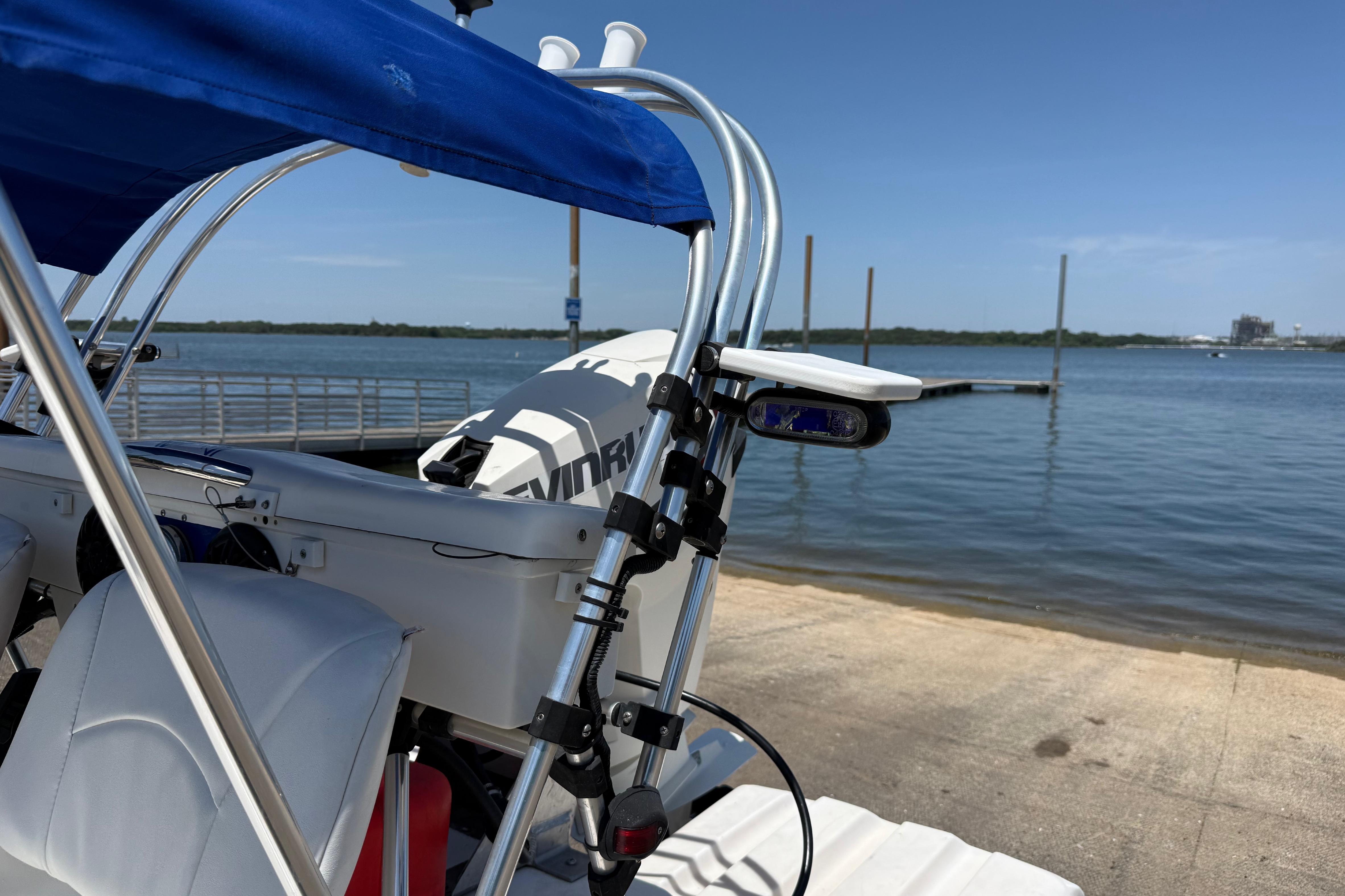 2016 CraigCat E2 Elite boat docked by a serene lake under a clear blue sky.