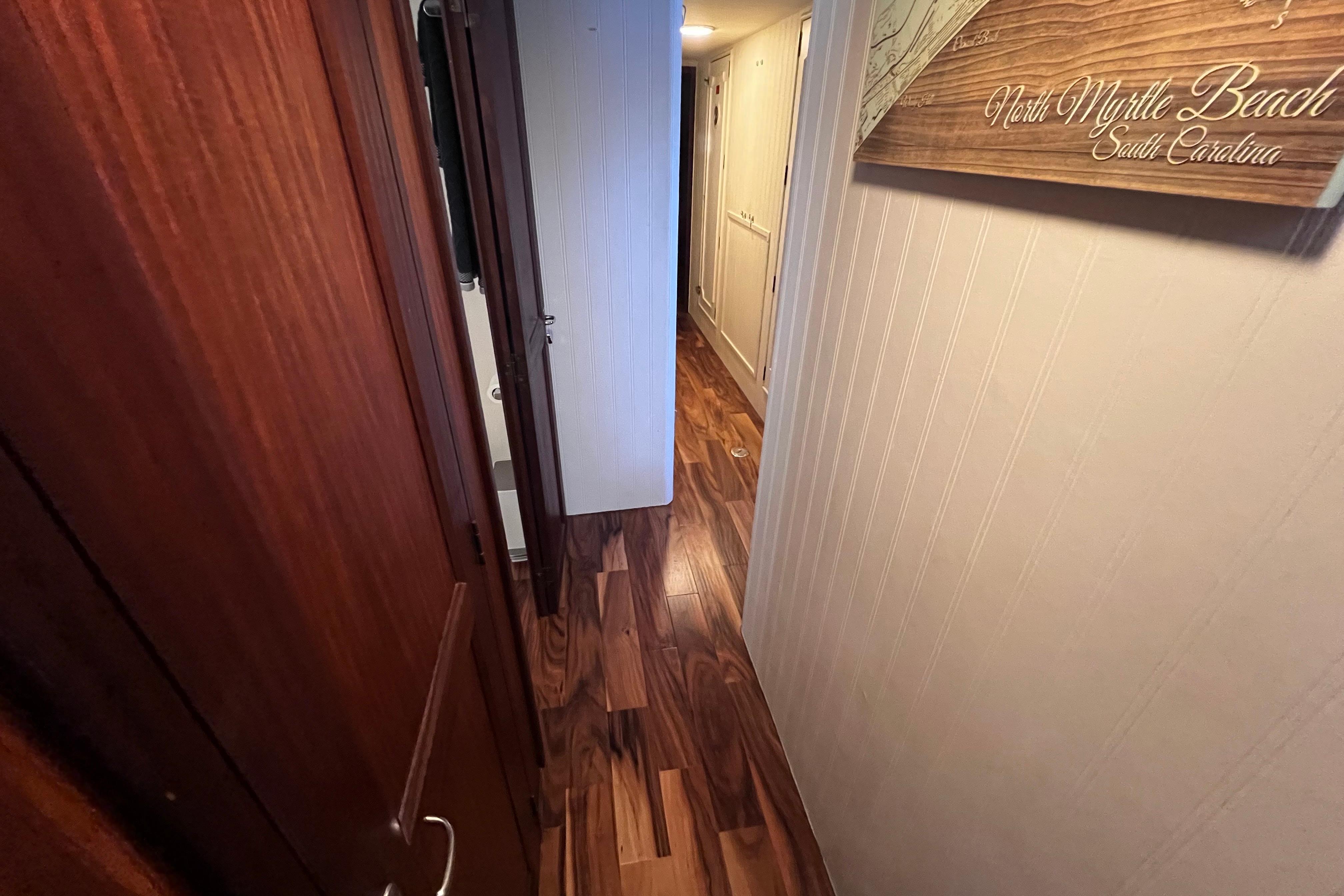 Narrow hallway inside 1987 Hatteras 70 Cockpit Motor Yacht with wooden flooring.