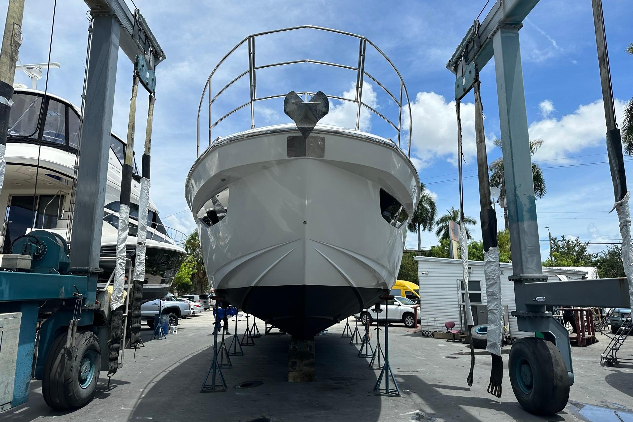 2013 Azimut Fly 53 yacht in dry dock, undergoing maintenance under a clear blue sky.