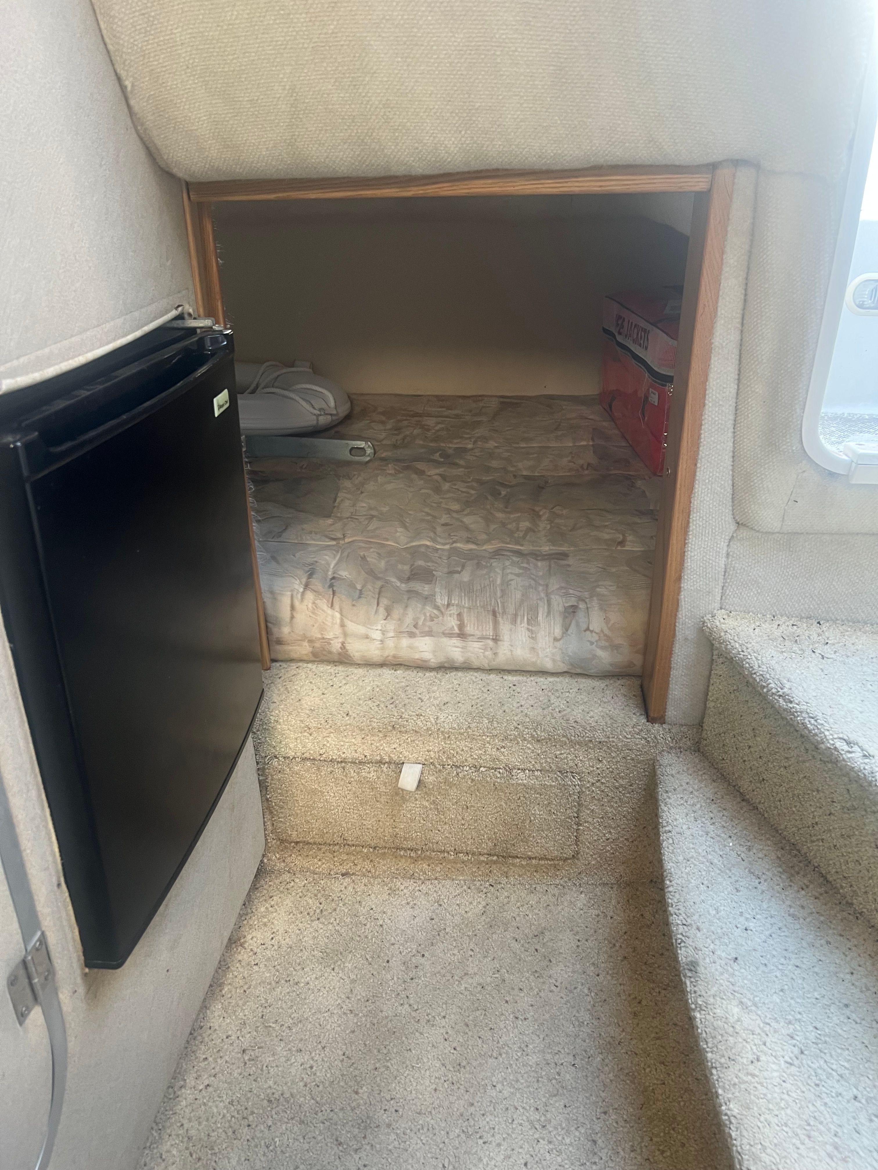 Interior of a 1995 MerCruiser Sc2400 with a sleeping area and refrigerator.