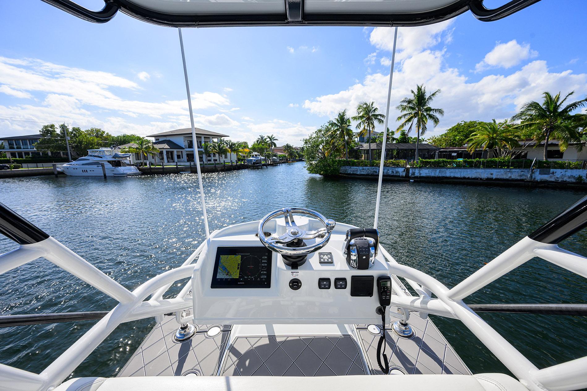 Cockpit view of 2021 Yellowfin 42 boat navigating a scenic waterway with palm trees.