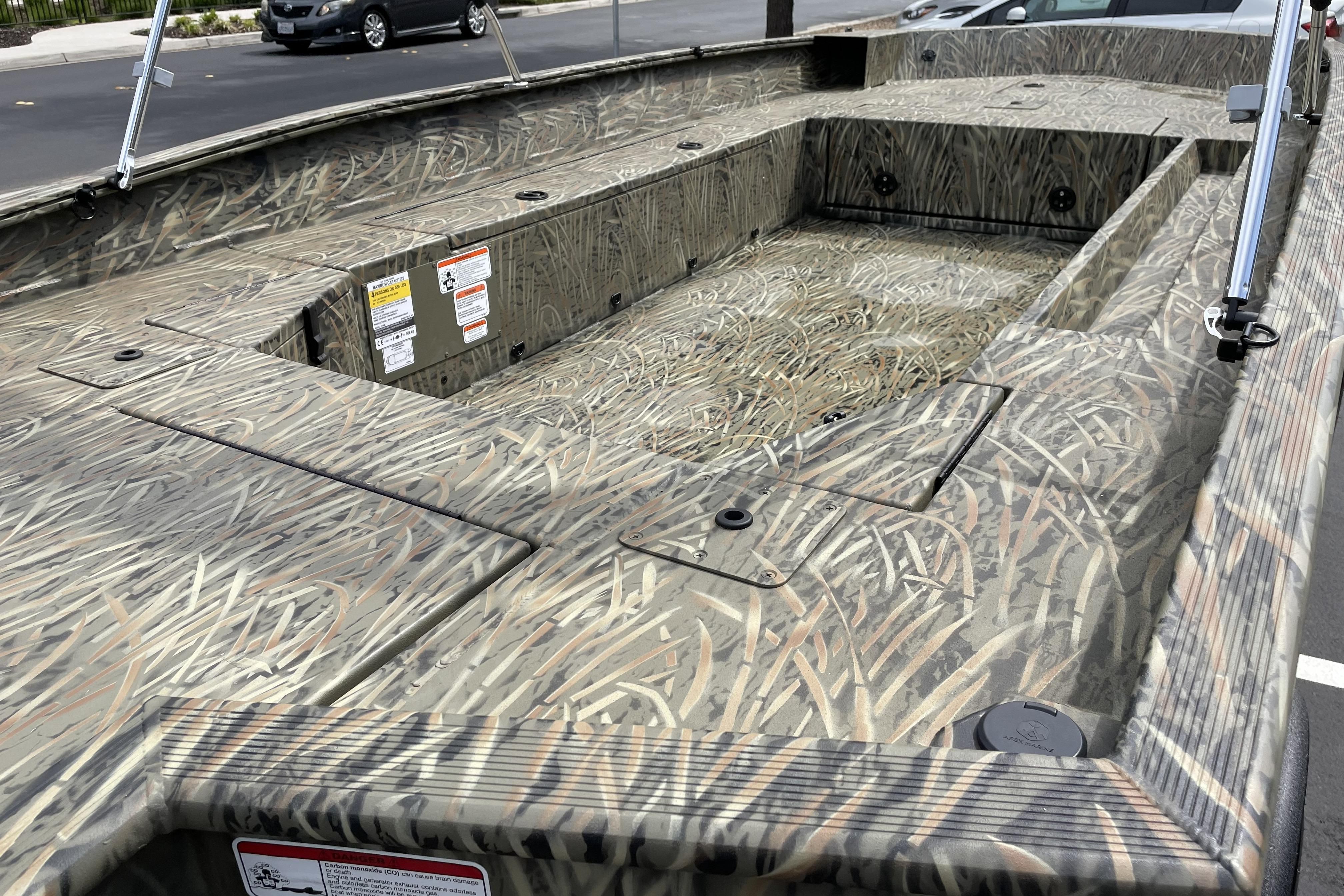2026 Tracker Grizzly 1756 T Marsh boat with camouflage design, parked outdoors.