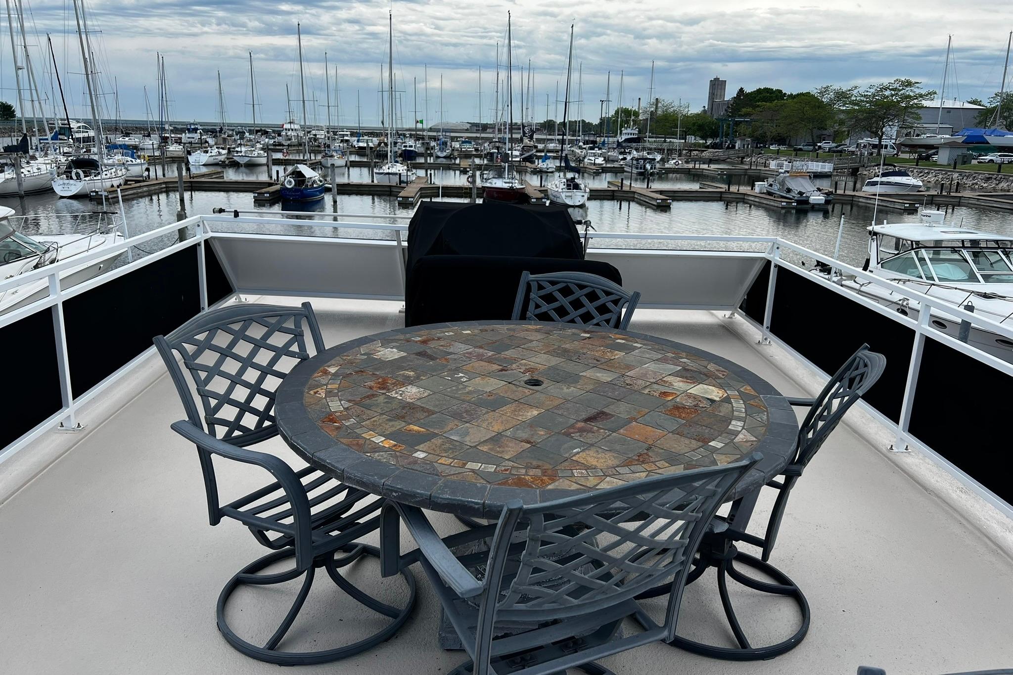 Flybridge of 2010 Skipperliner 480 with mosaic table, overlooking marina with docked boats.