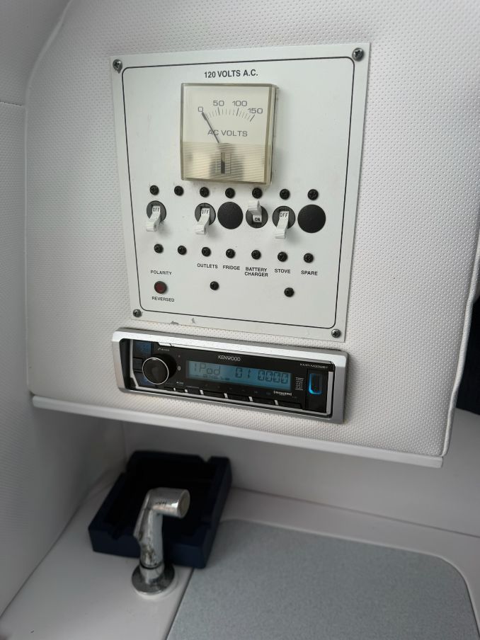 A control panel with voltage meter and switches, below a Kenwood car stereo.