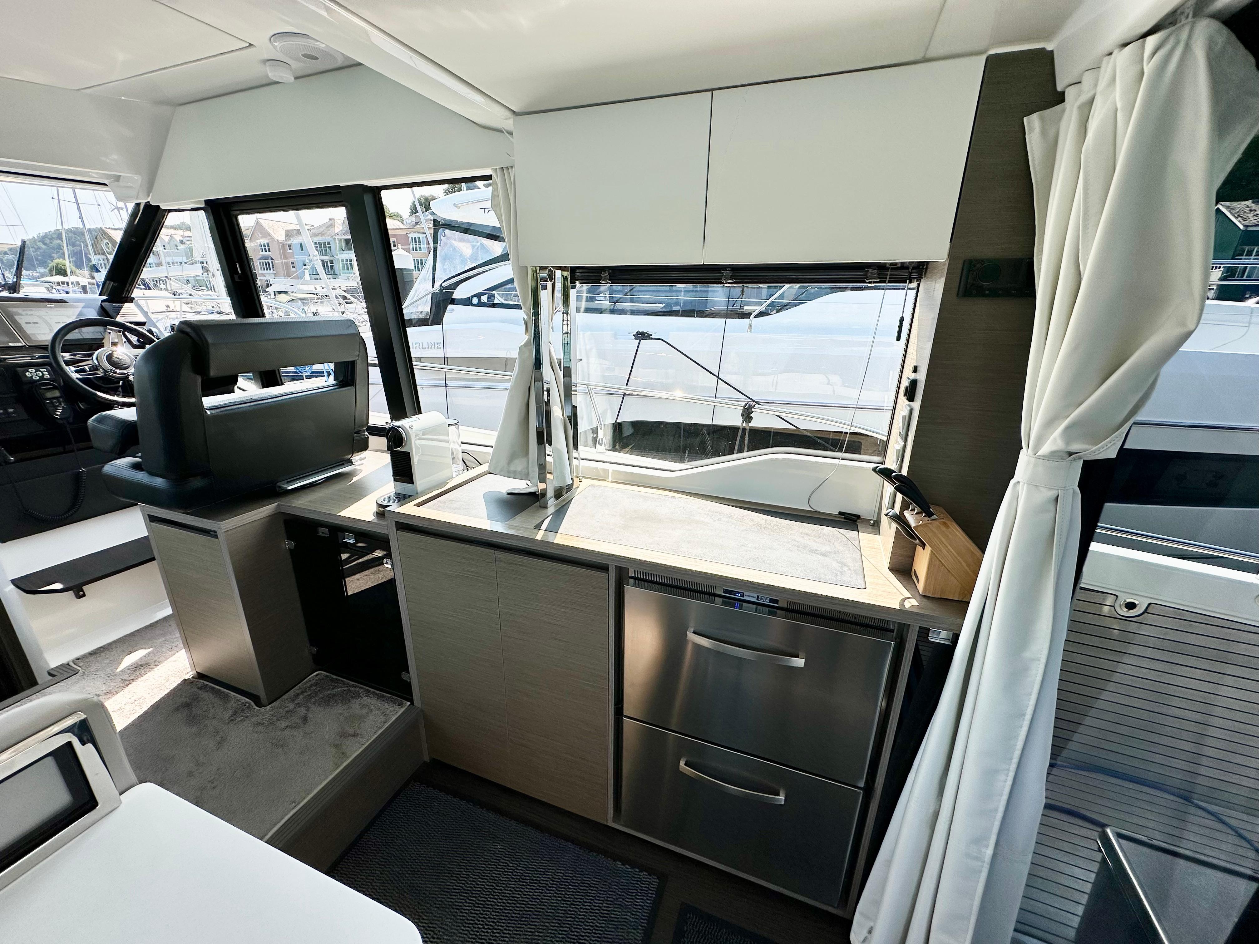 2024 Jeanneau Merry Fisher 1295 Flybridge interior with modern kitchen and helm station.