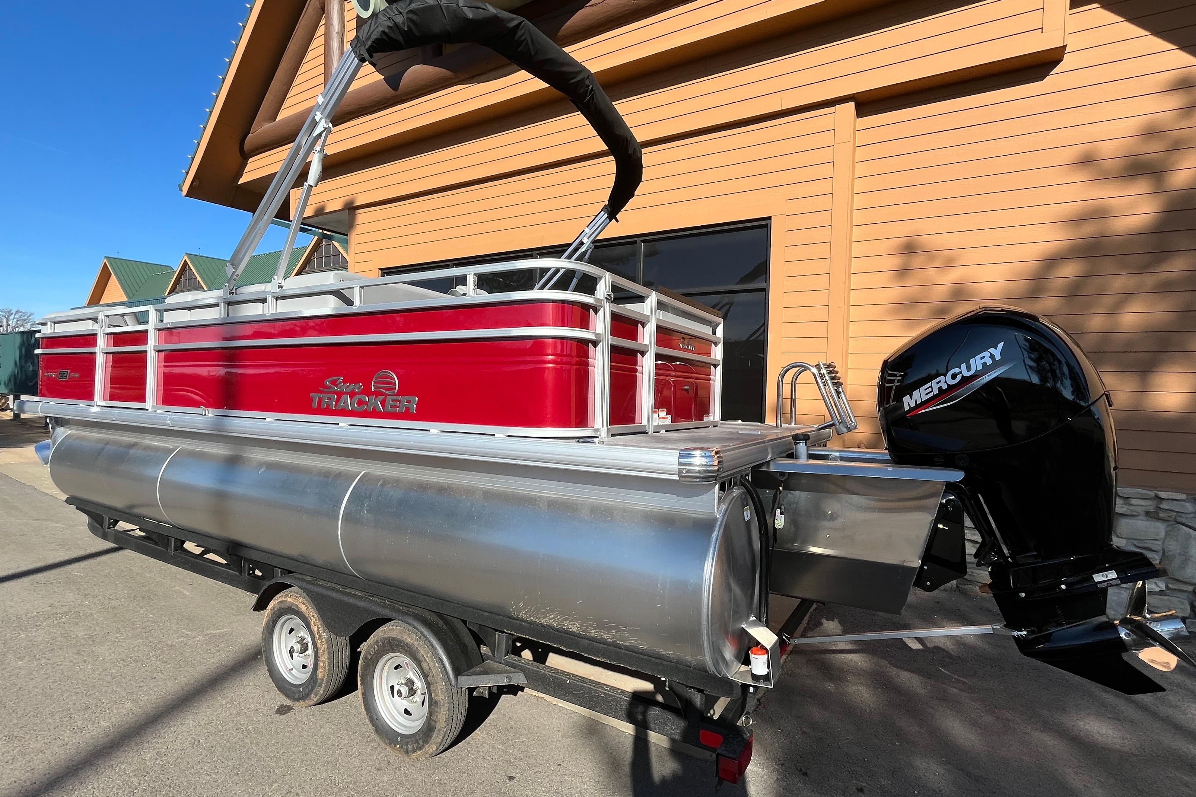 2026 Sun Tracker SportFish 22 XP3 pontoon boat with Mercury engine, parked outdoors.