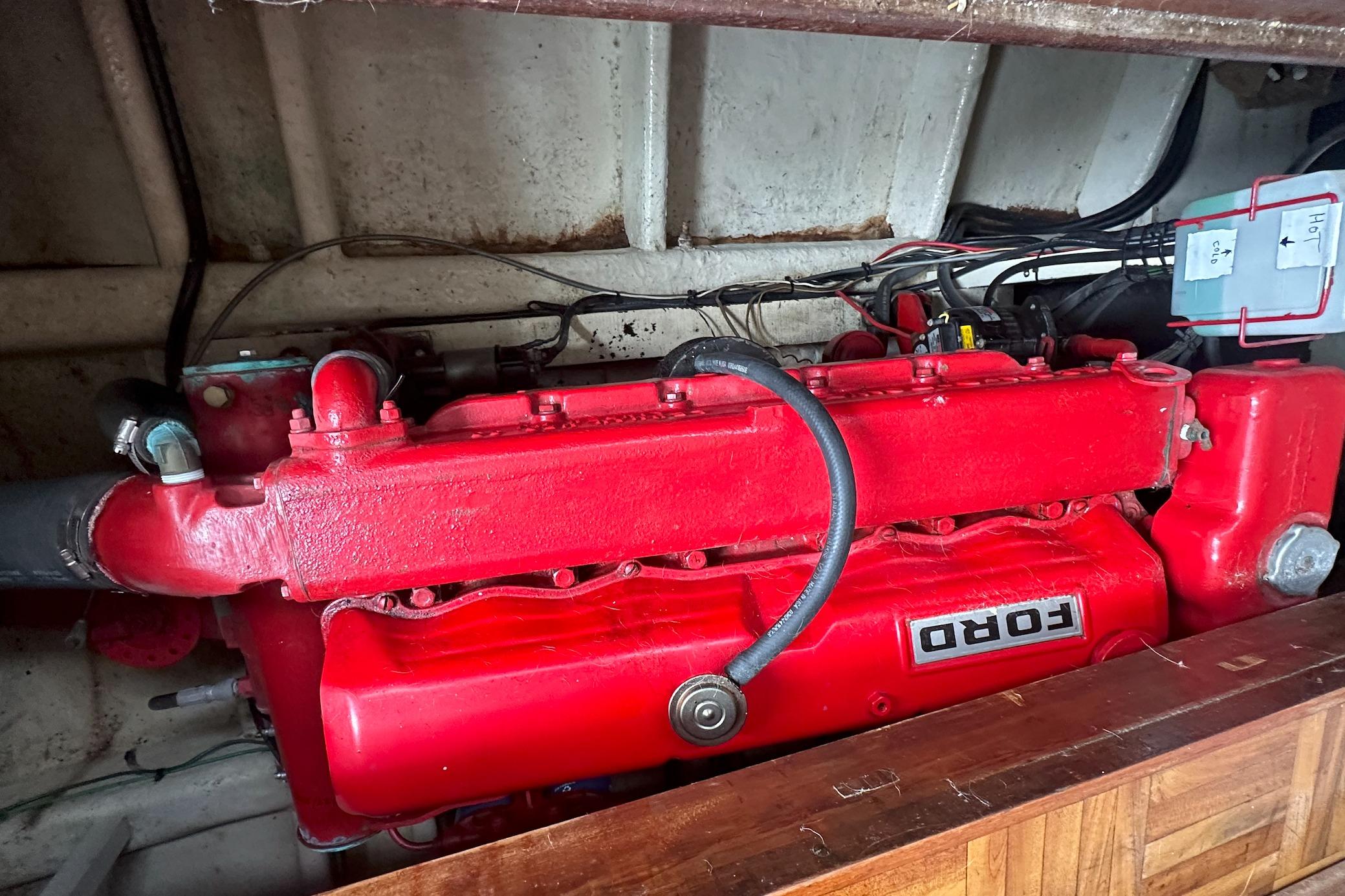 Red Ford engine inside a 1973 CHB 33 boat, showcasing mechanical components.