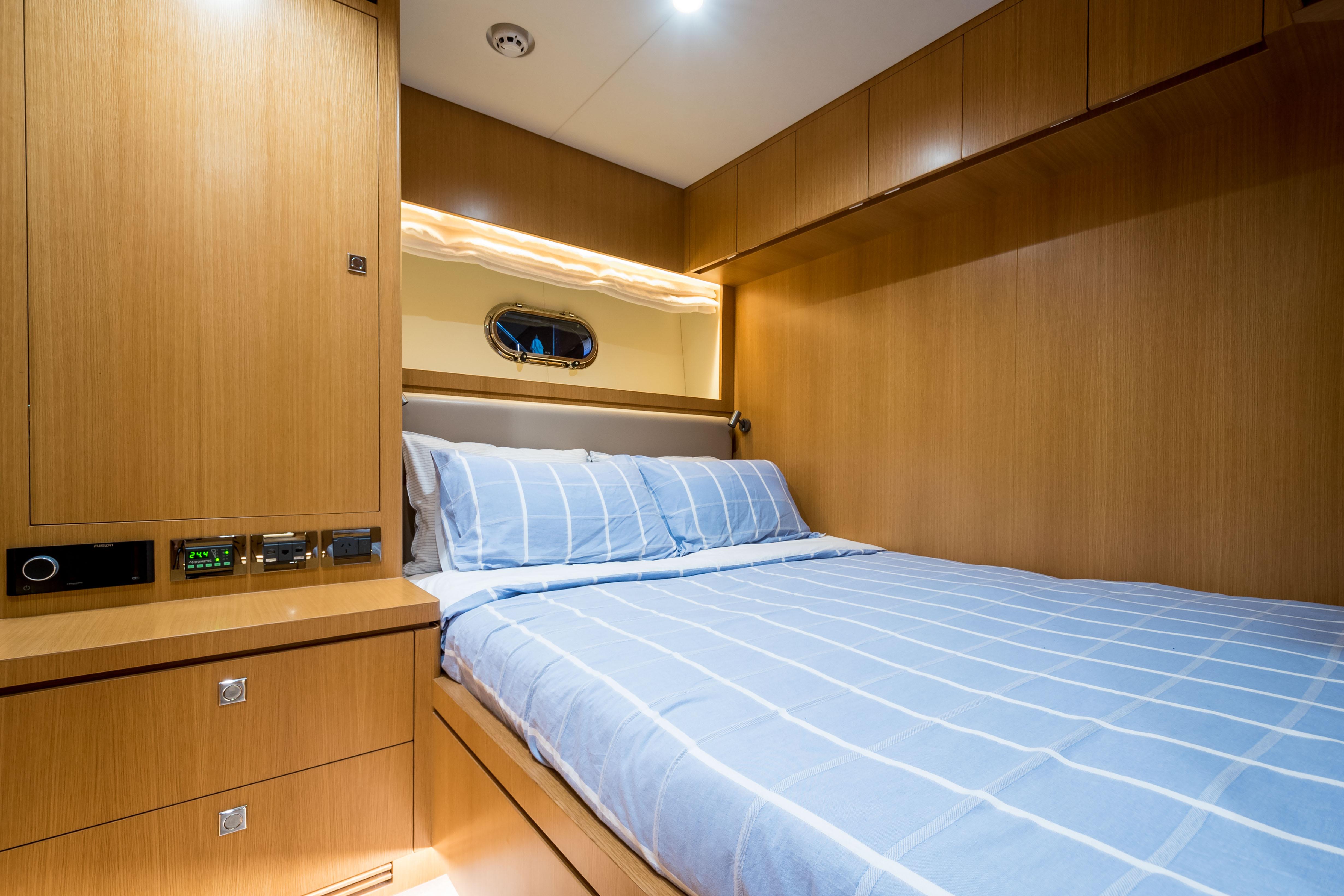 Luxurious cabin interior of 2020 Horizon RP100 yacht with wood paneling and striped bedding.