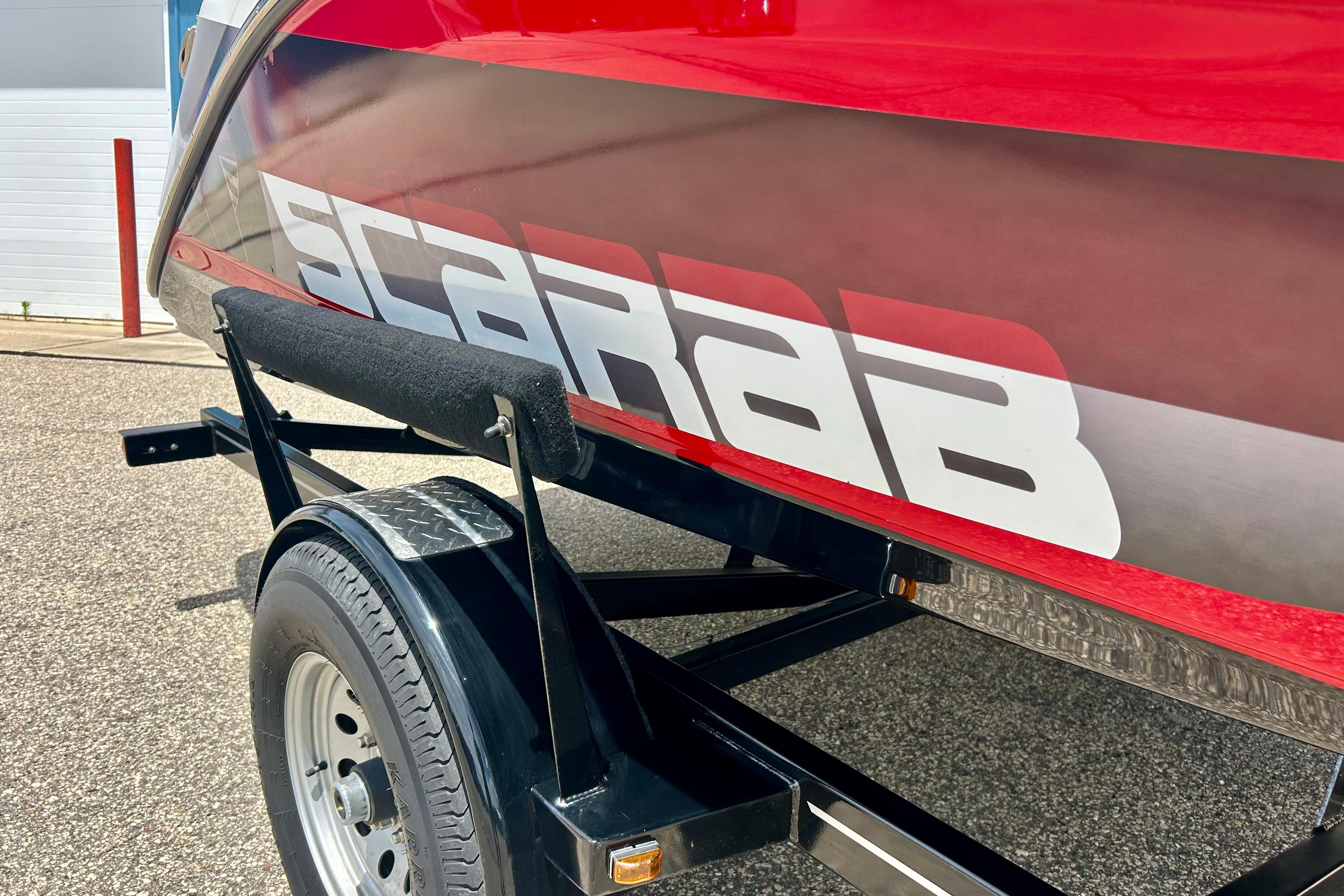 Red and black 2021 Scarab 195 ID boat on trailer, showcasing bold branding.
