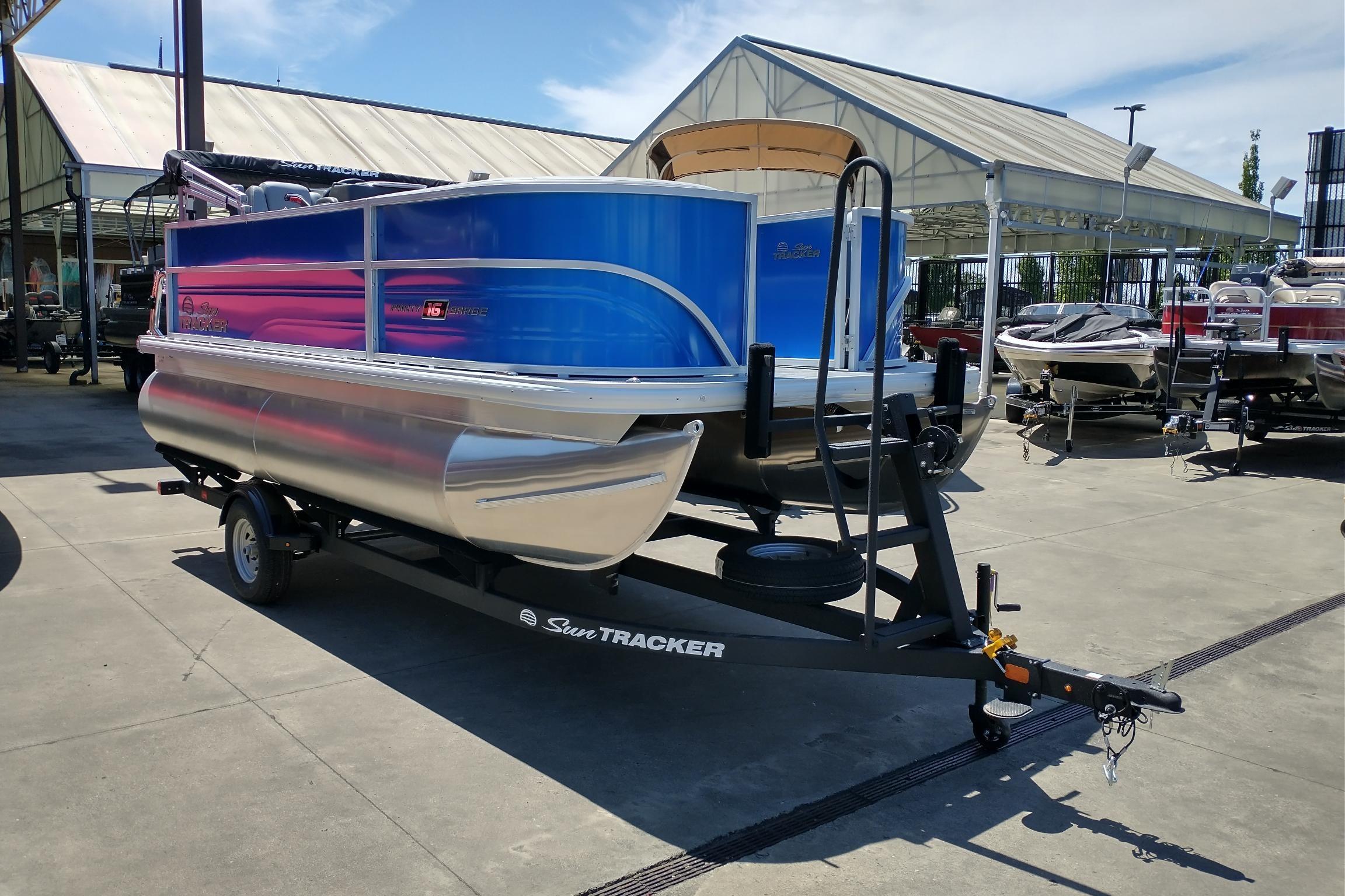 2026 Sun Tracker Party Barge 16 DLX pontoon boat on trailer at dealership.