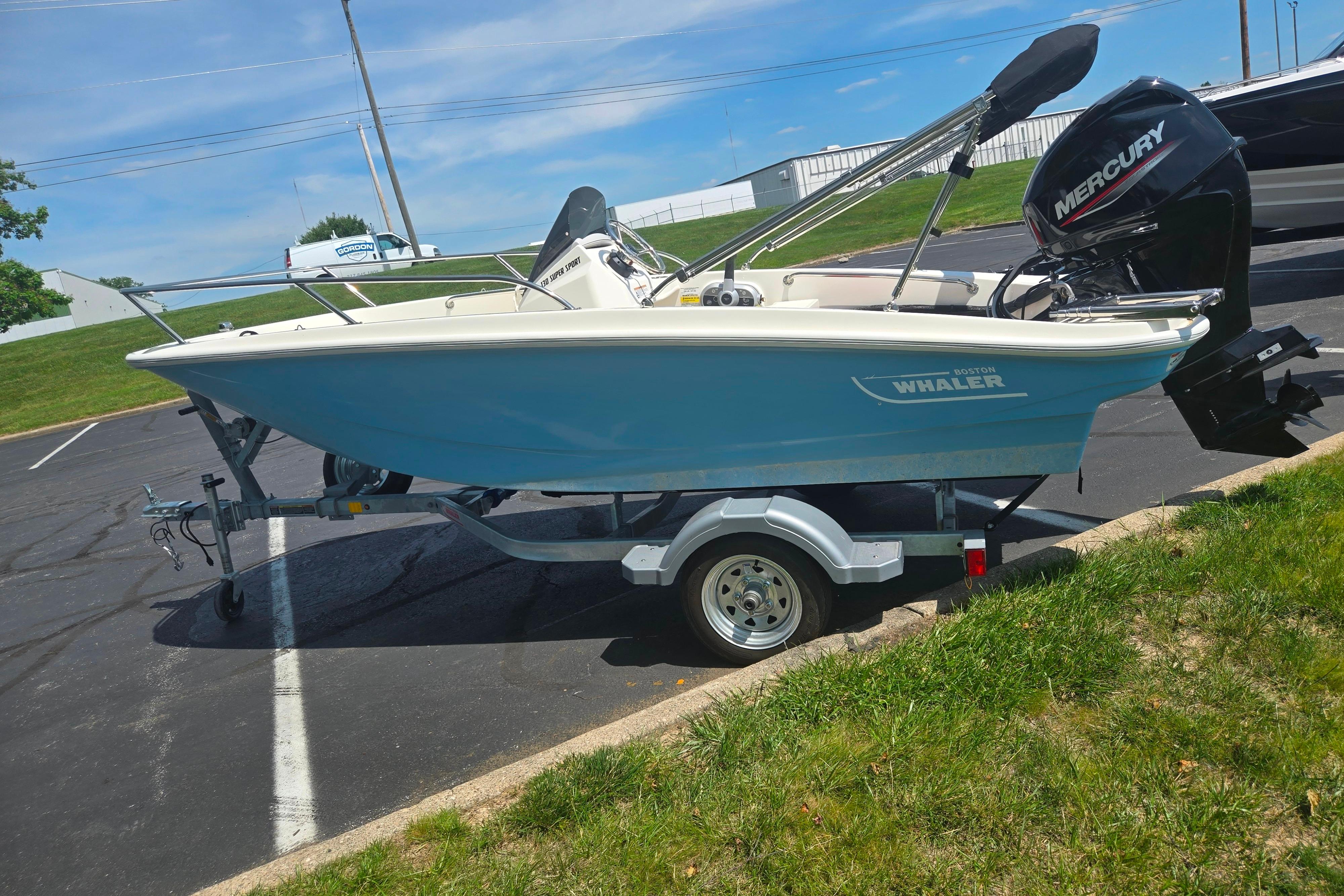 2025 Boston Whaler 130 Super Sport boat on trailer, parked outdoors.