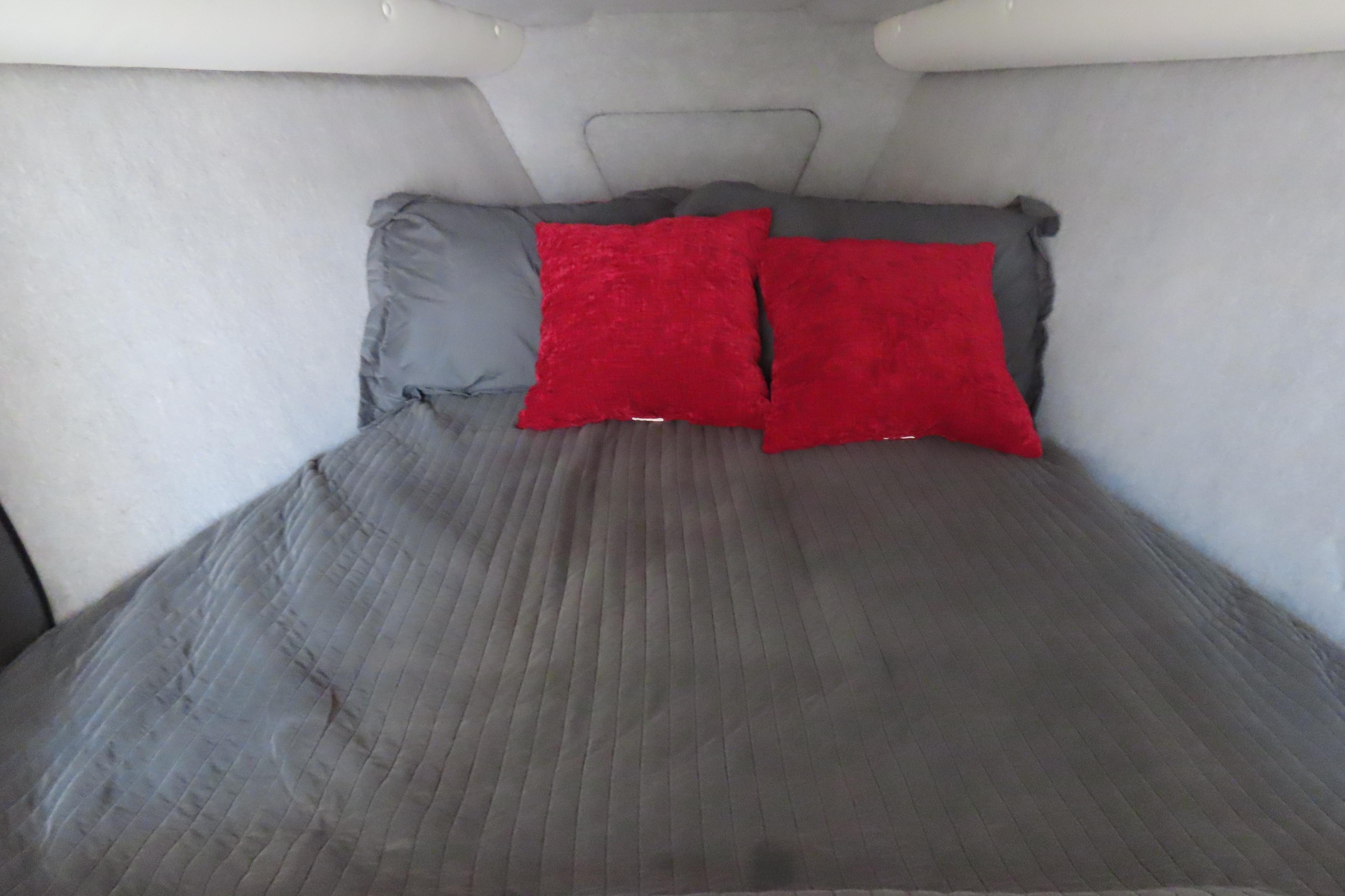 Cozy cabin bed in 2013 Nordic 39 Poker Run boat with red pillows and gray bedding.