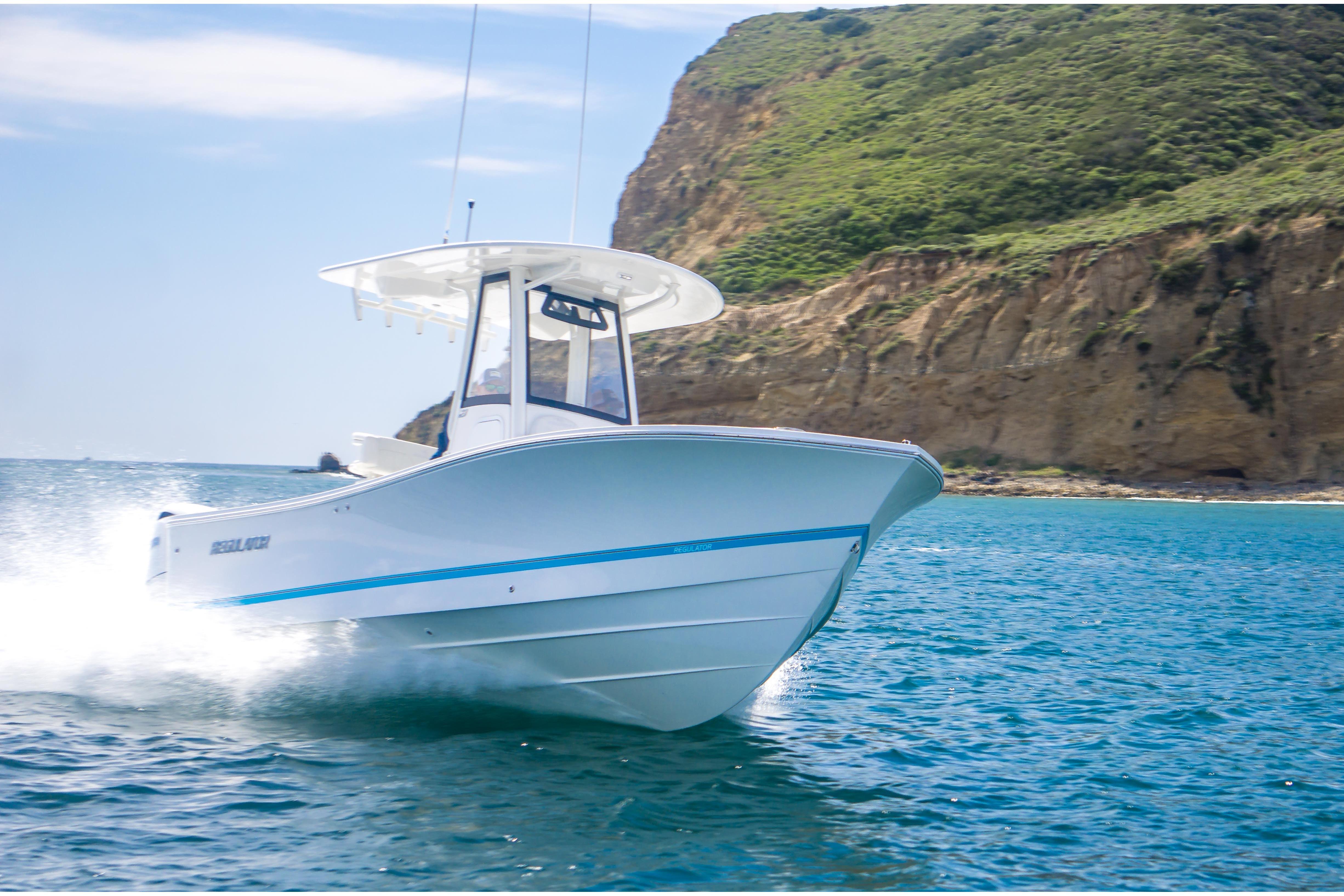2026 Regulator 23 boat cruising near rocky coastline in clear blue waters.