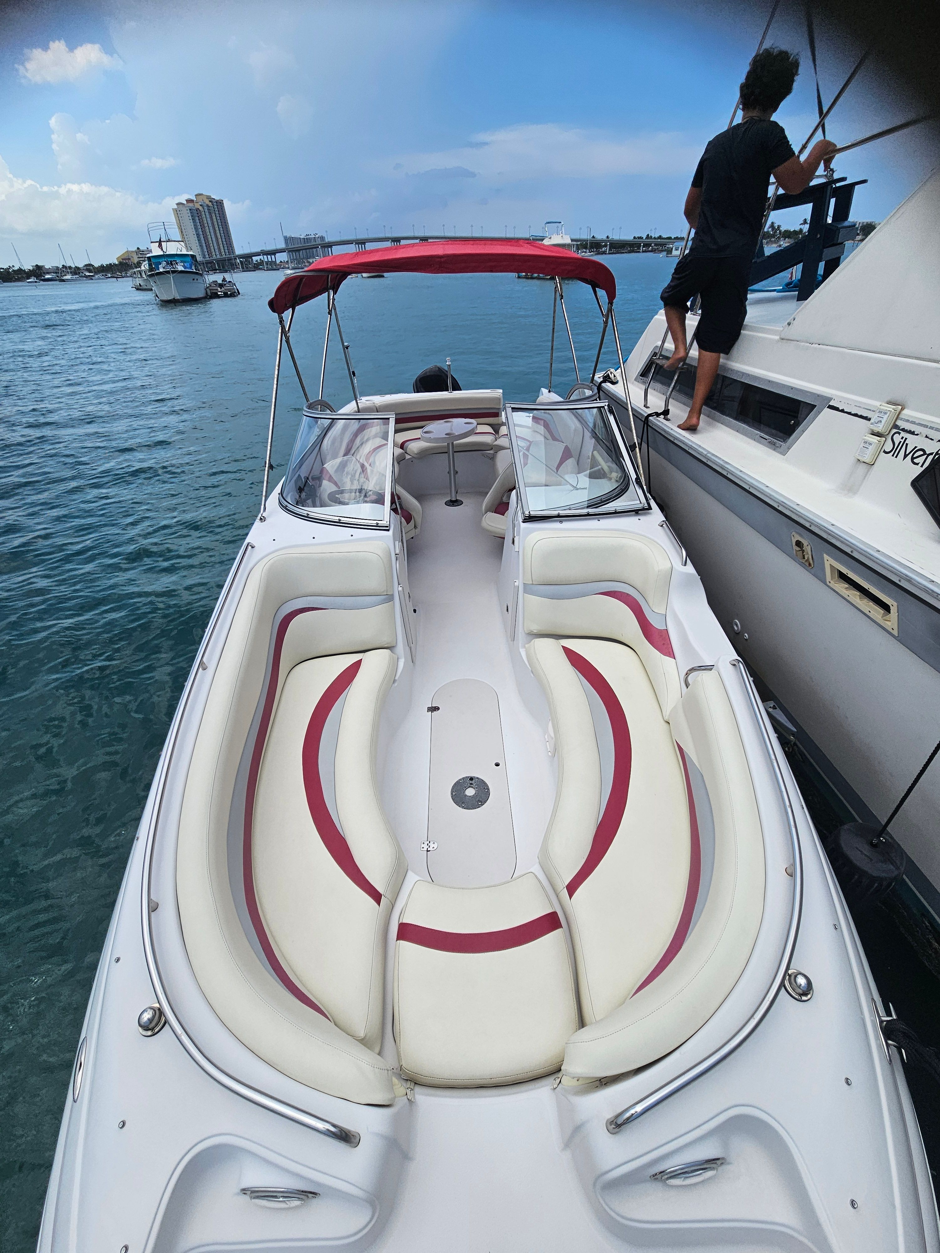 A boat with red and white seating is docked next to another boat on the water.