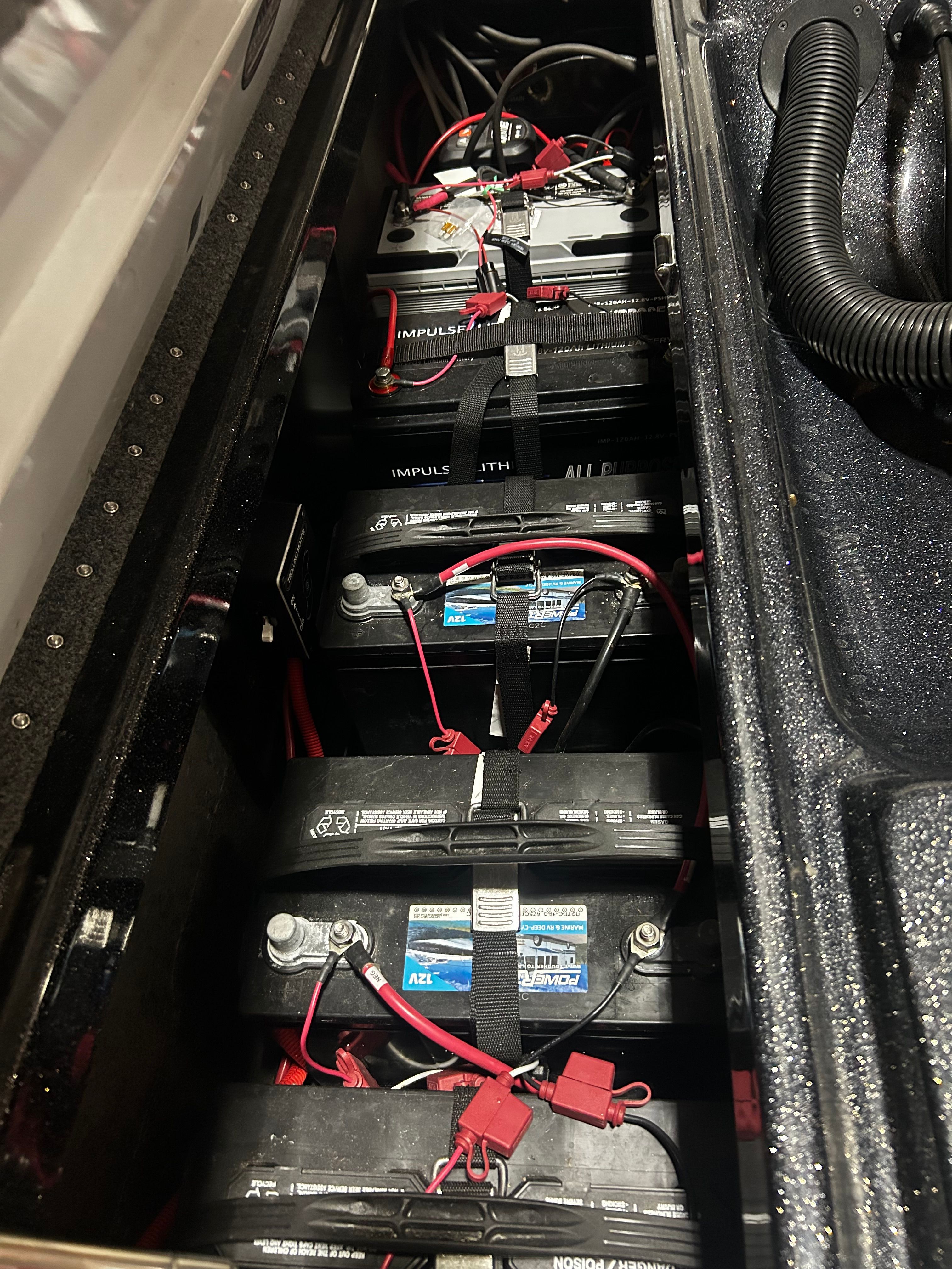 Battery compartment of a Phoenix 921 Elite boat with multiple batteries and cables.