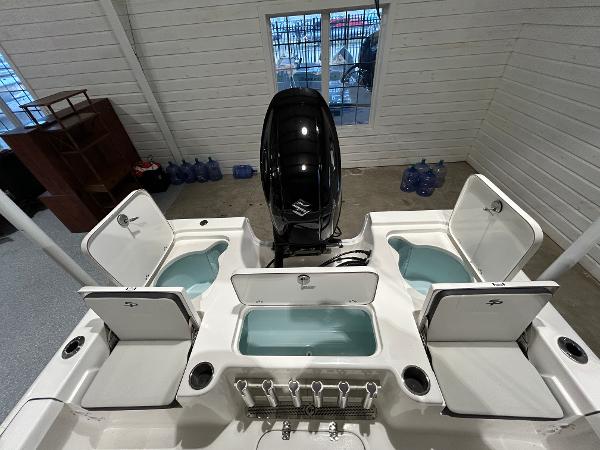 2025 Sea Pro 210 Bay boat with open storage compartments and outboard motor in a garage.
