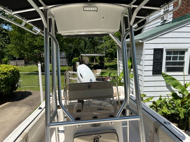 A 2022 Carolina Skiff 21 Ultra Elite with T-top and outboard motor, parked in a garden.