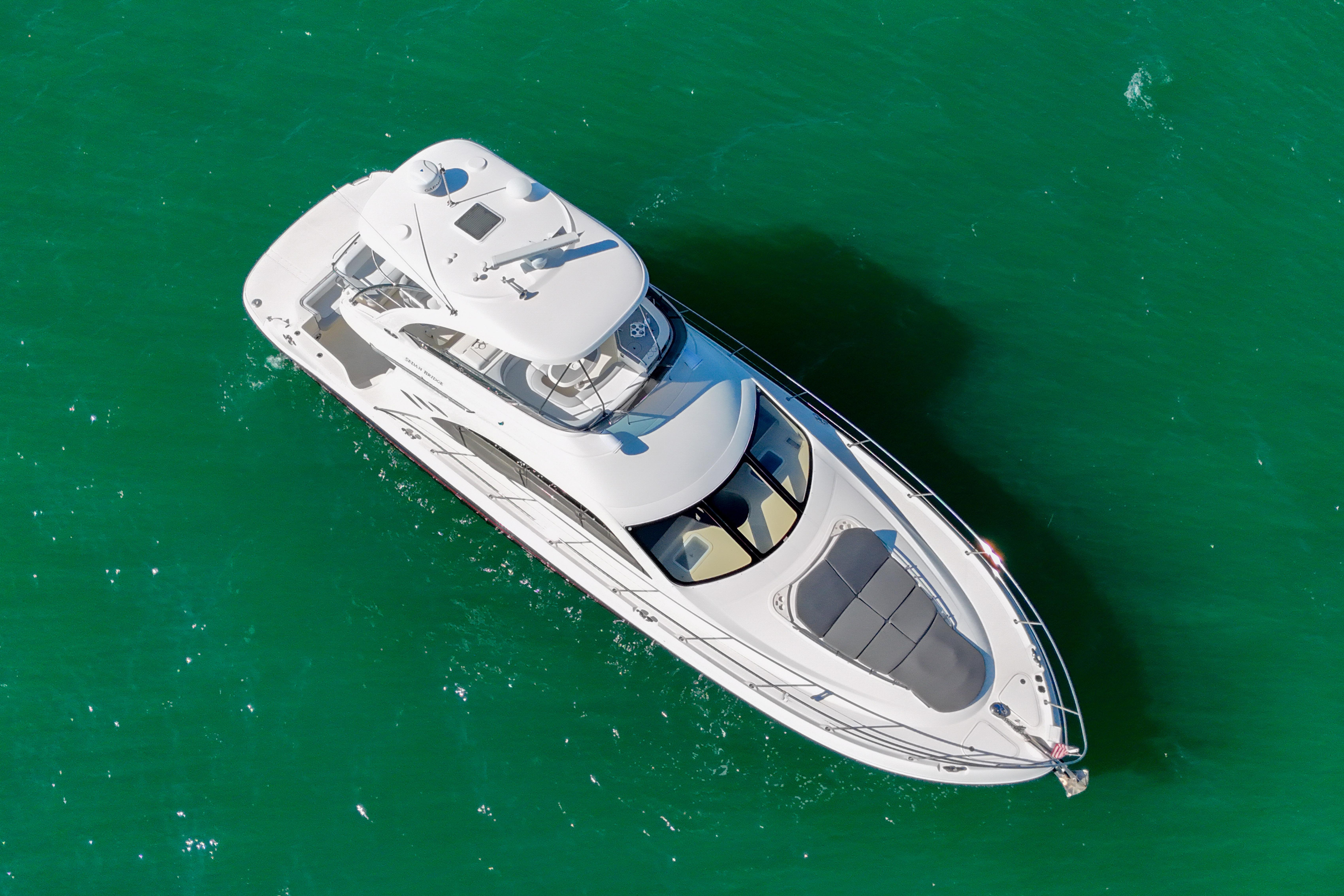 Aerial view of 2007 Sea Ray 52 Sedan Bridge yacht on green water.
