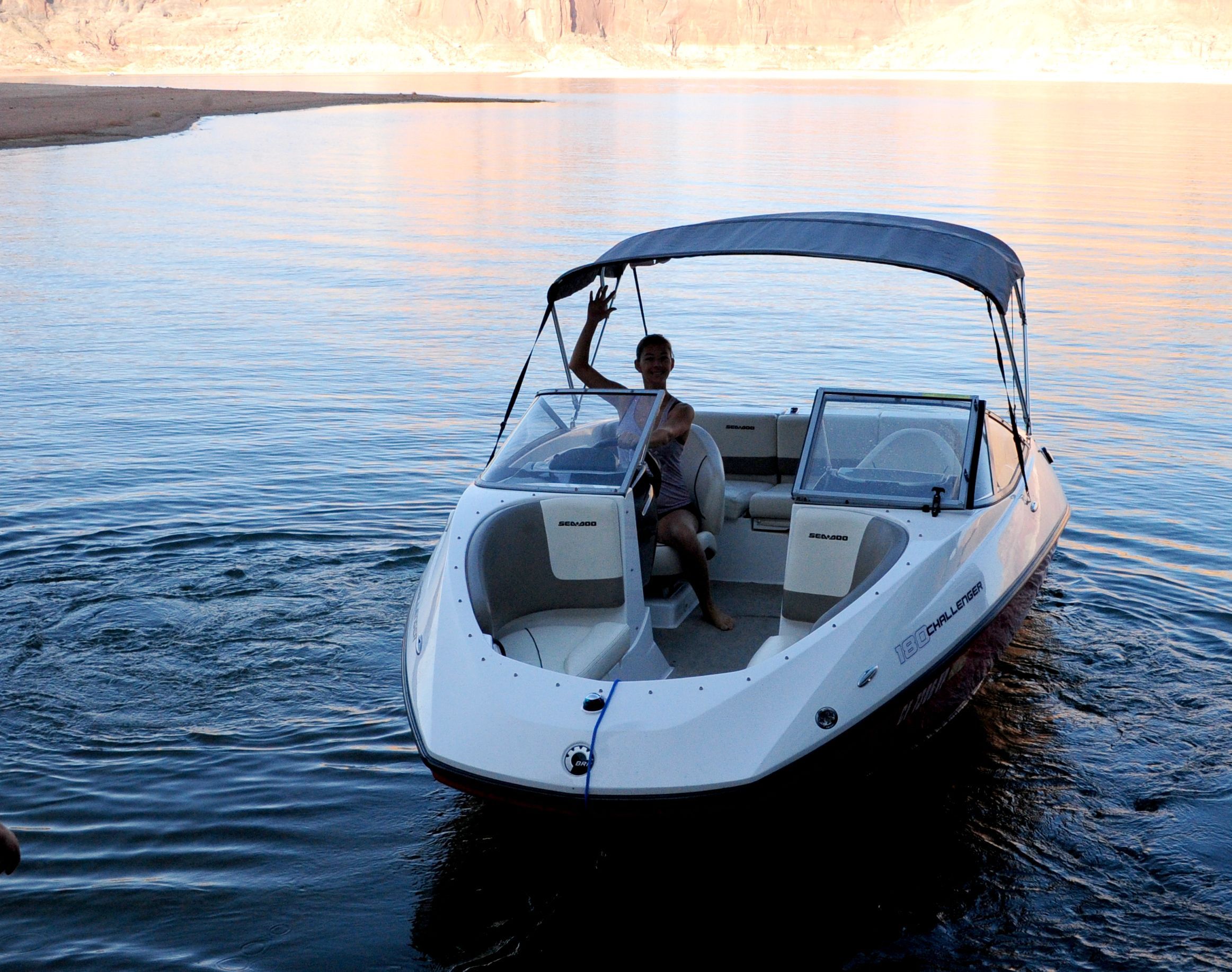 A white motorboat with a gray sunshade navigates calm waters.