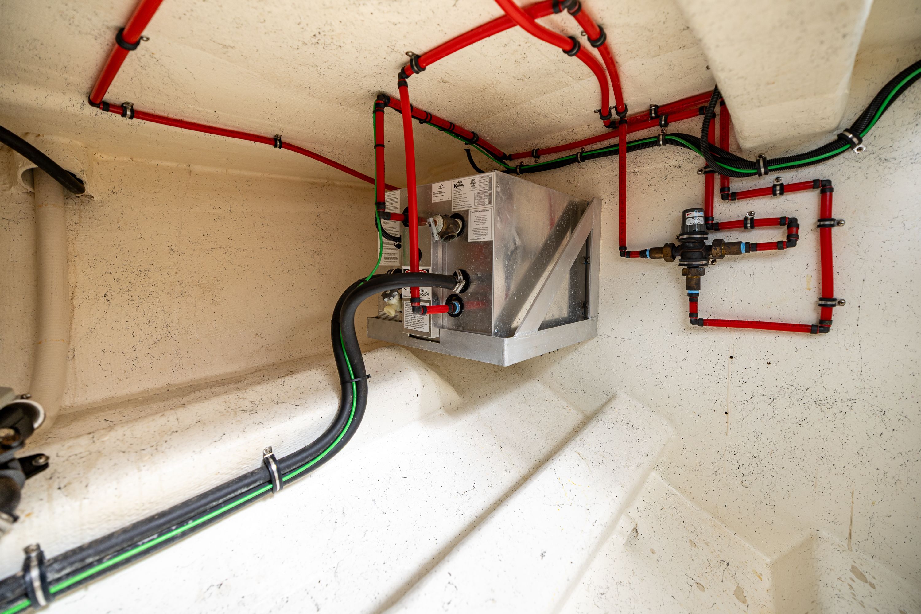 A clean engine room with colored pipes and a metal box.