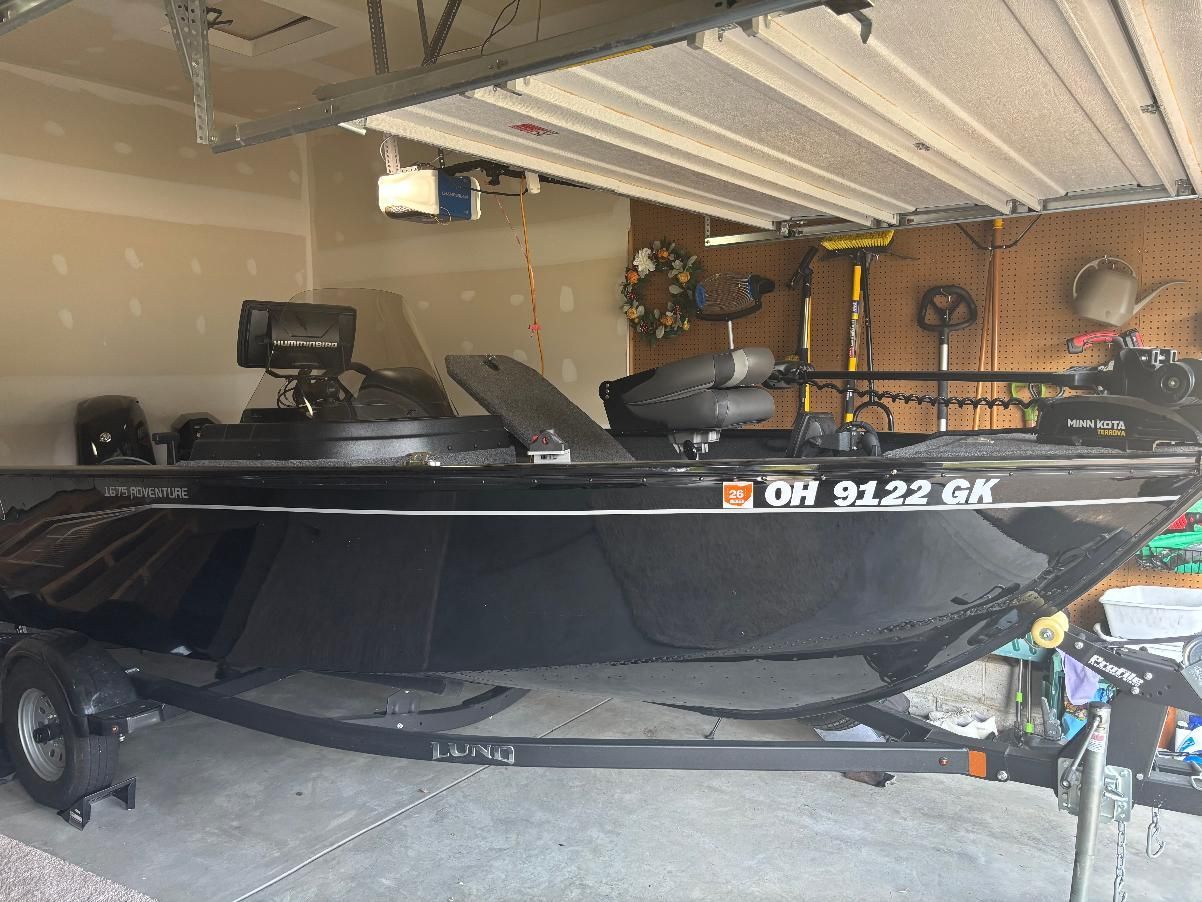 A black Lund Advent boat, model year 2022, is parked in a garage.
