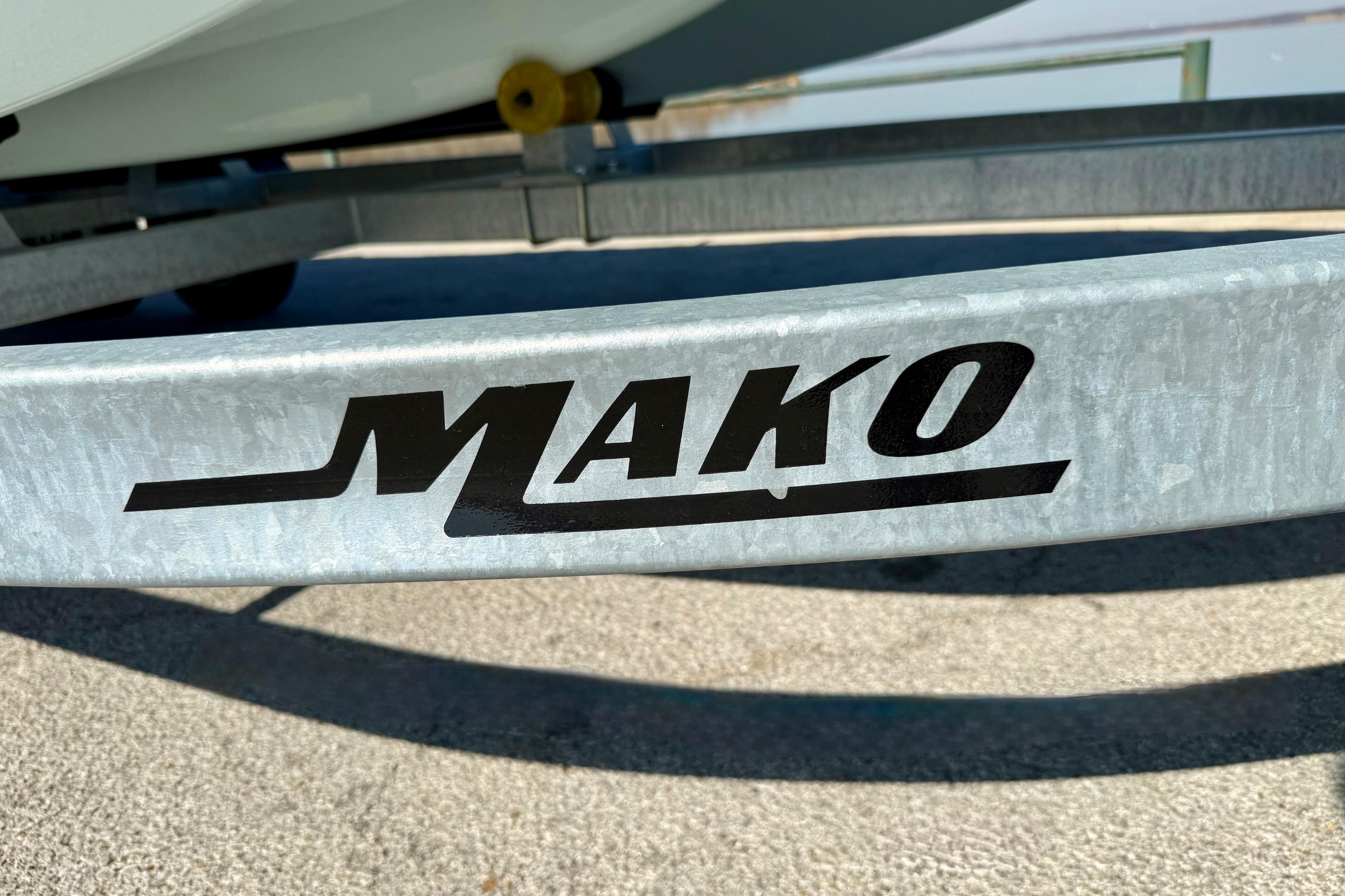 2024 Mako Pro Skiff 19 CC trailer with logo, parked on concrete surface.