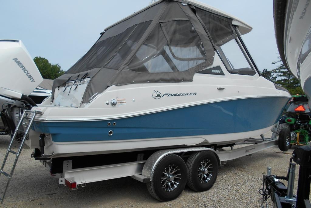 2024 Finseeker 280 DC boat on trailer, featuring blue and white design with canopy.