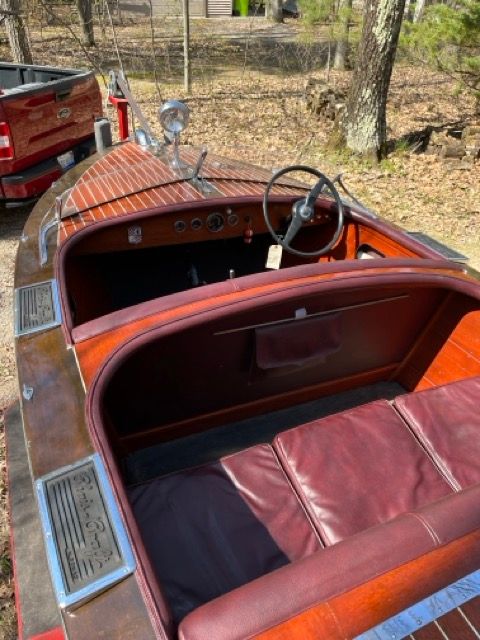 A classic 1938 Chris-Craft Custom Deluxe Runabout with polished wood accents and red leather.