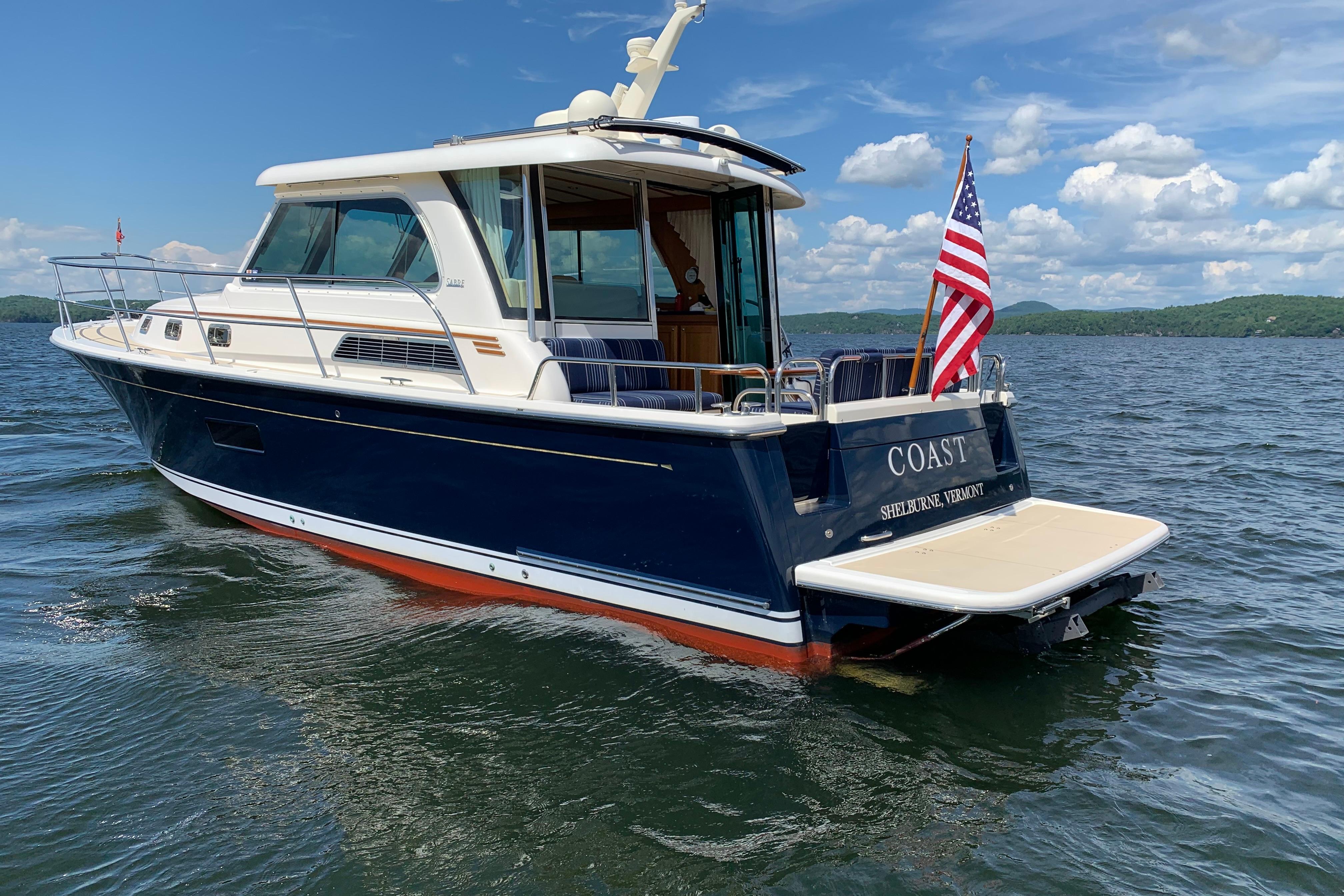 2015 Sabre 38 Salon Express yacht on water, displaying American flag, under blue sky.