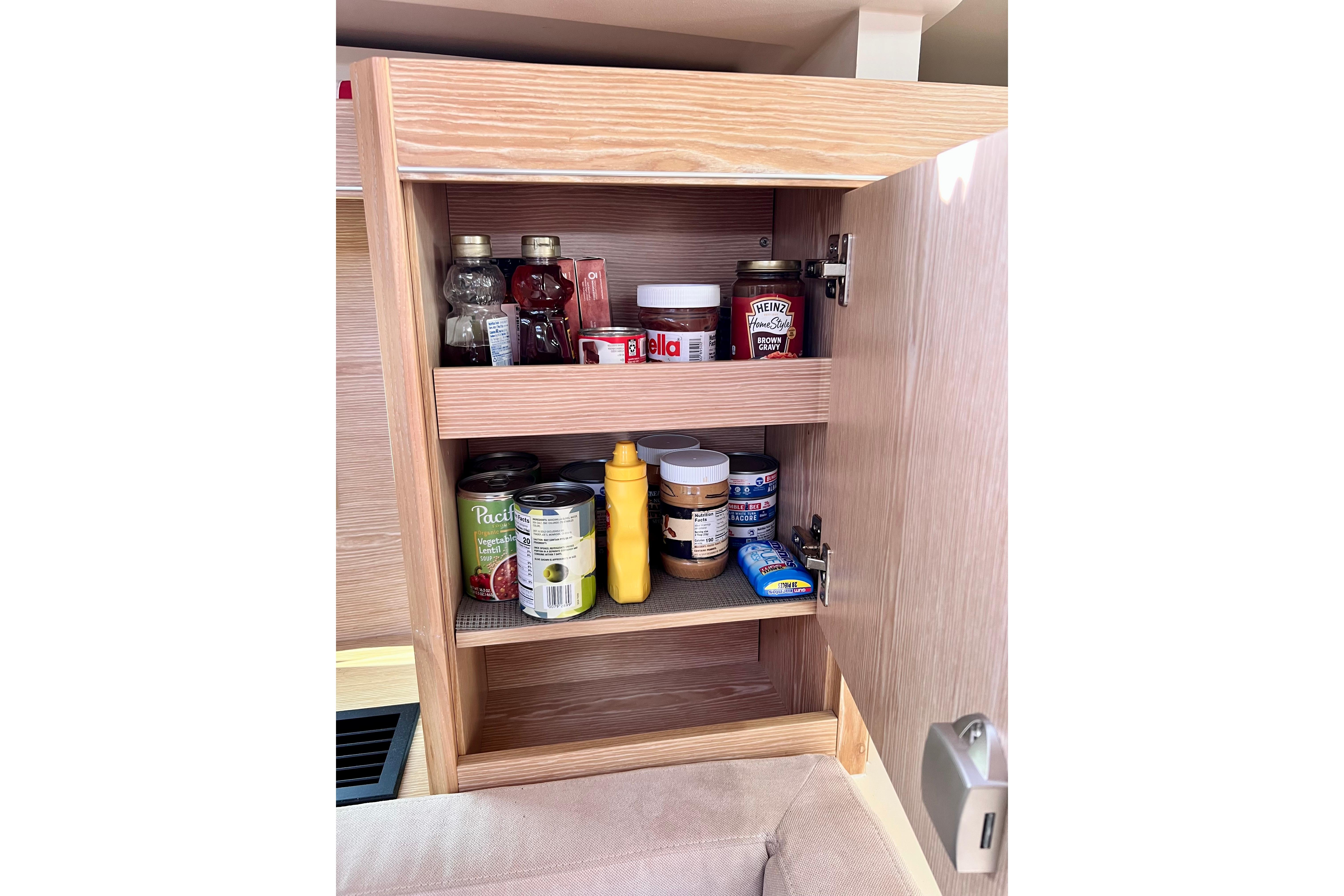 Wooden cabinet in 2016 Hanse 455 yacht, stocked with condiments and canned goods.