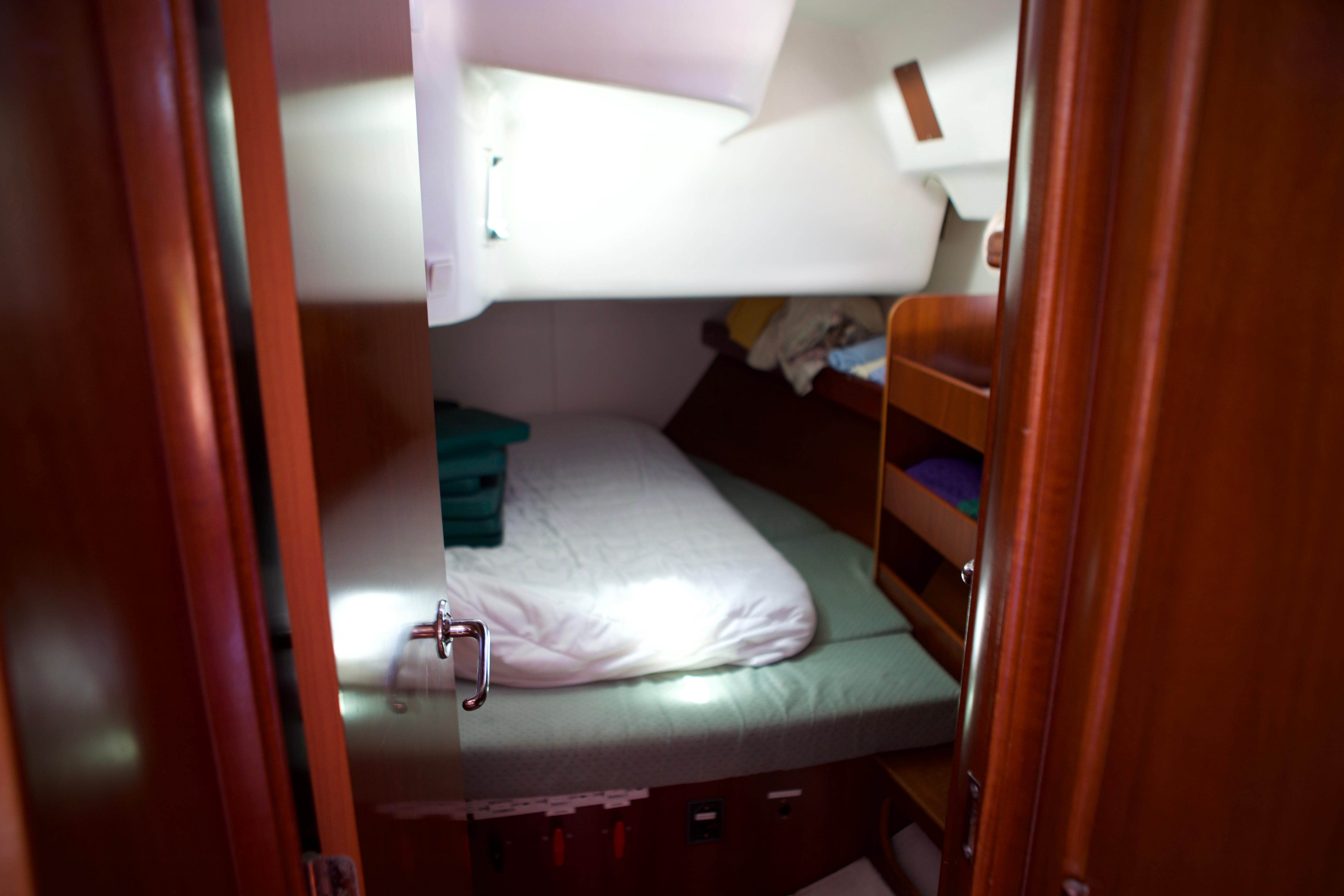 Cozy cabin interior of 2005 Beneteau 423 sailboat with bed and wooden storage.