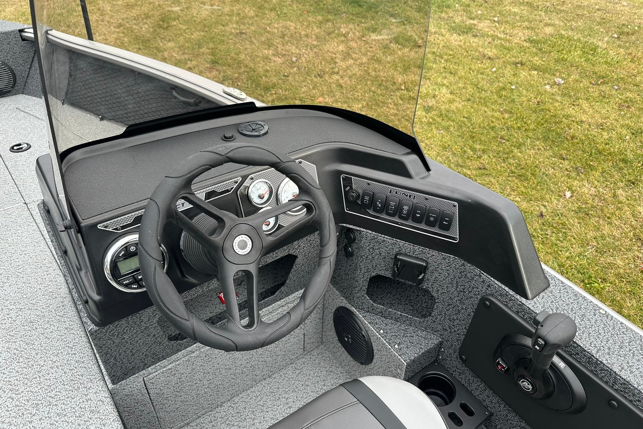 2026 Lund 1875 Impact XS SS boat dashboard with steering wheel and control panel.